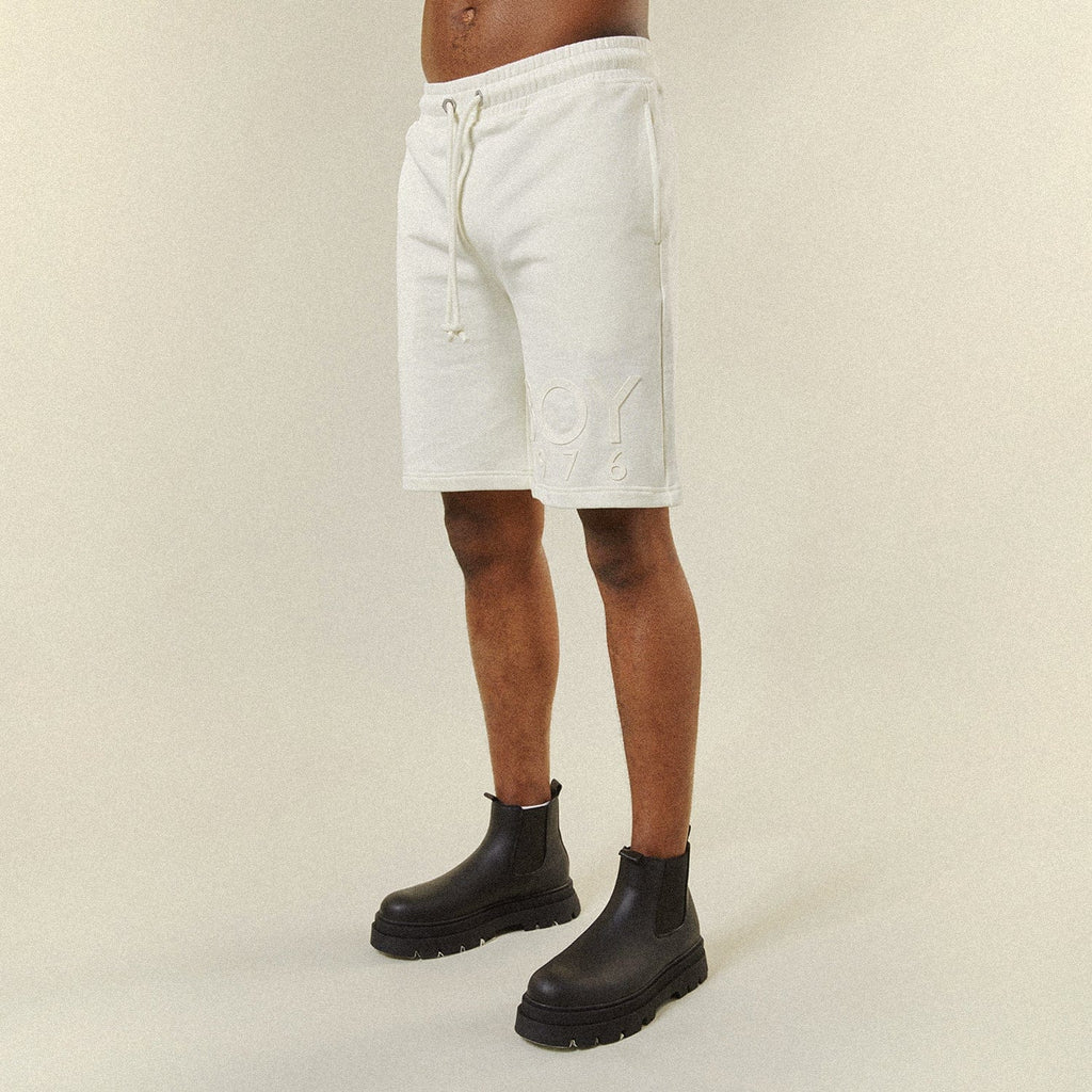 Model wearing BOY London shorts on plain background