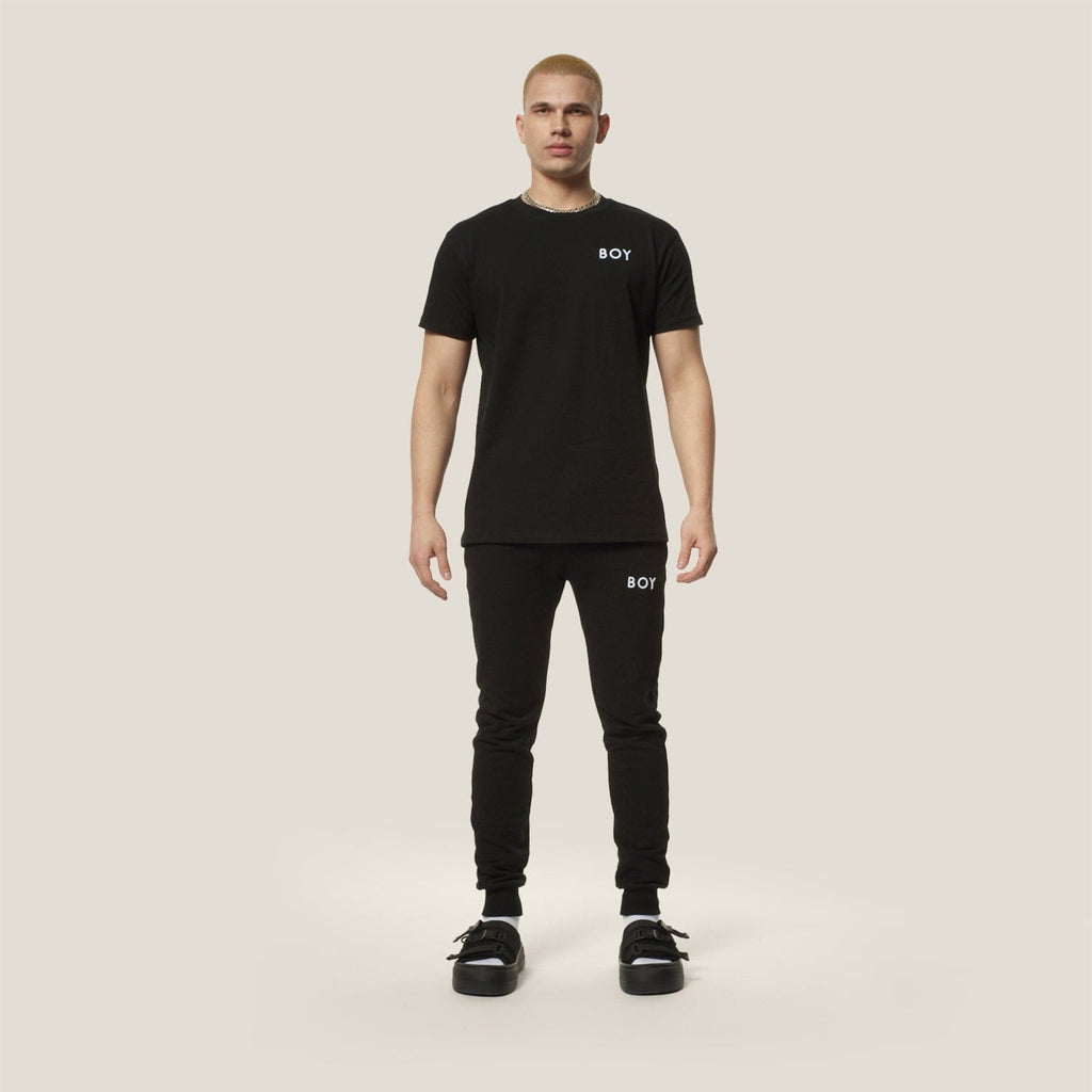 Model wearing black boy london joggers on plain background