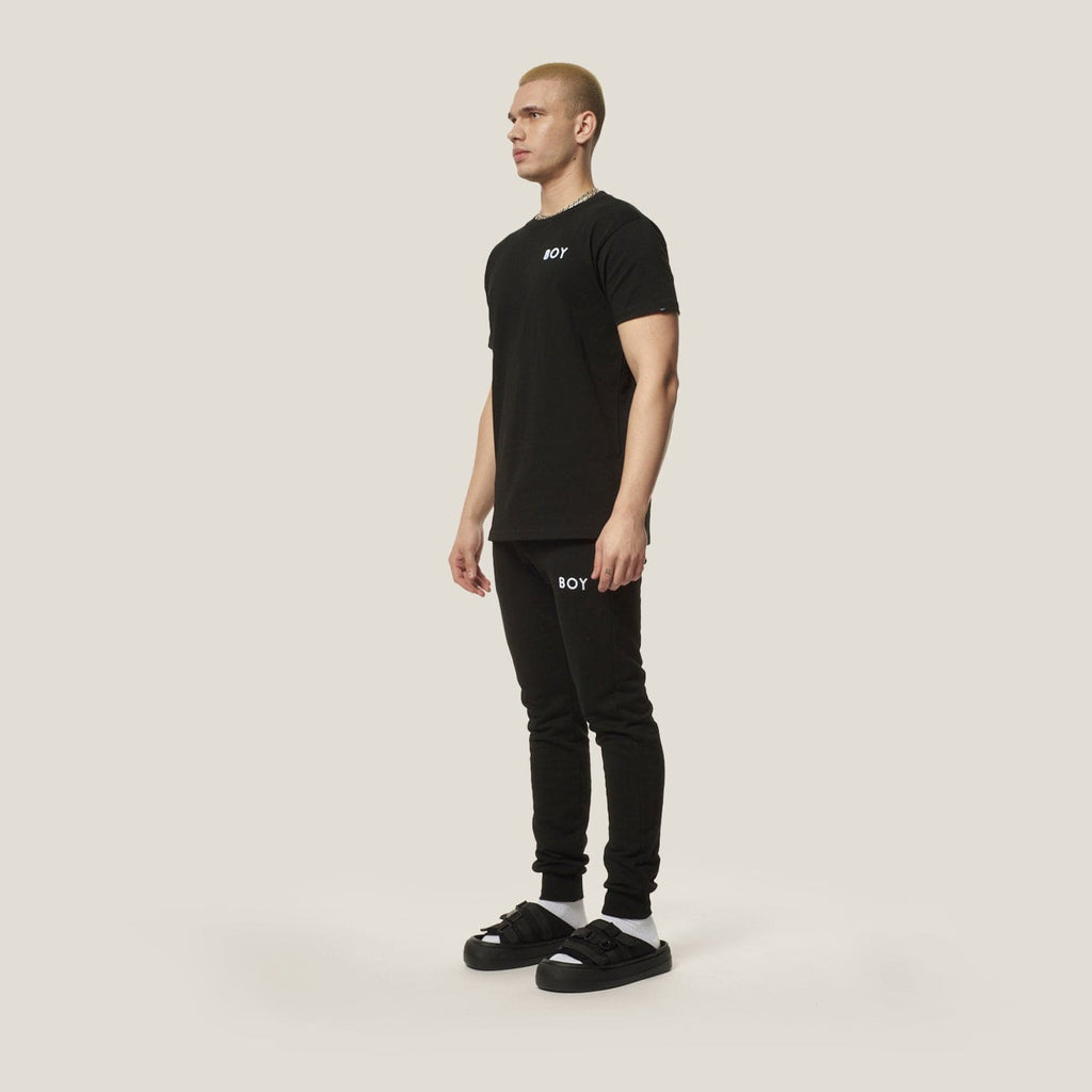 Model wearing black boy london joggers on plain background