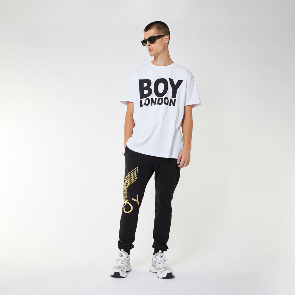 Model wearing Black BOY London sweatpants with gold design on a white background