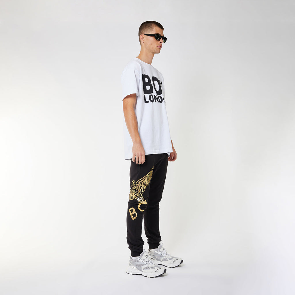 Model wearing Black BOY London sweatpants with gold design on a white background