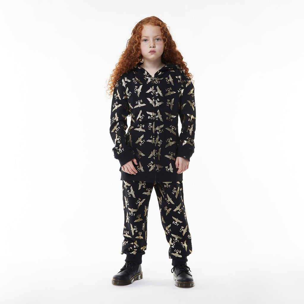 Model wearing Black Boy London pants with yellow airplane pattern on a white background