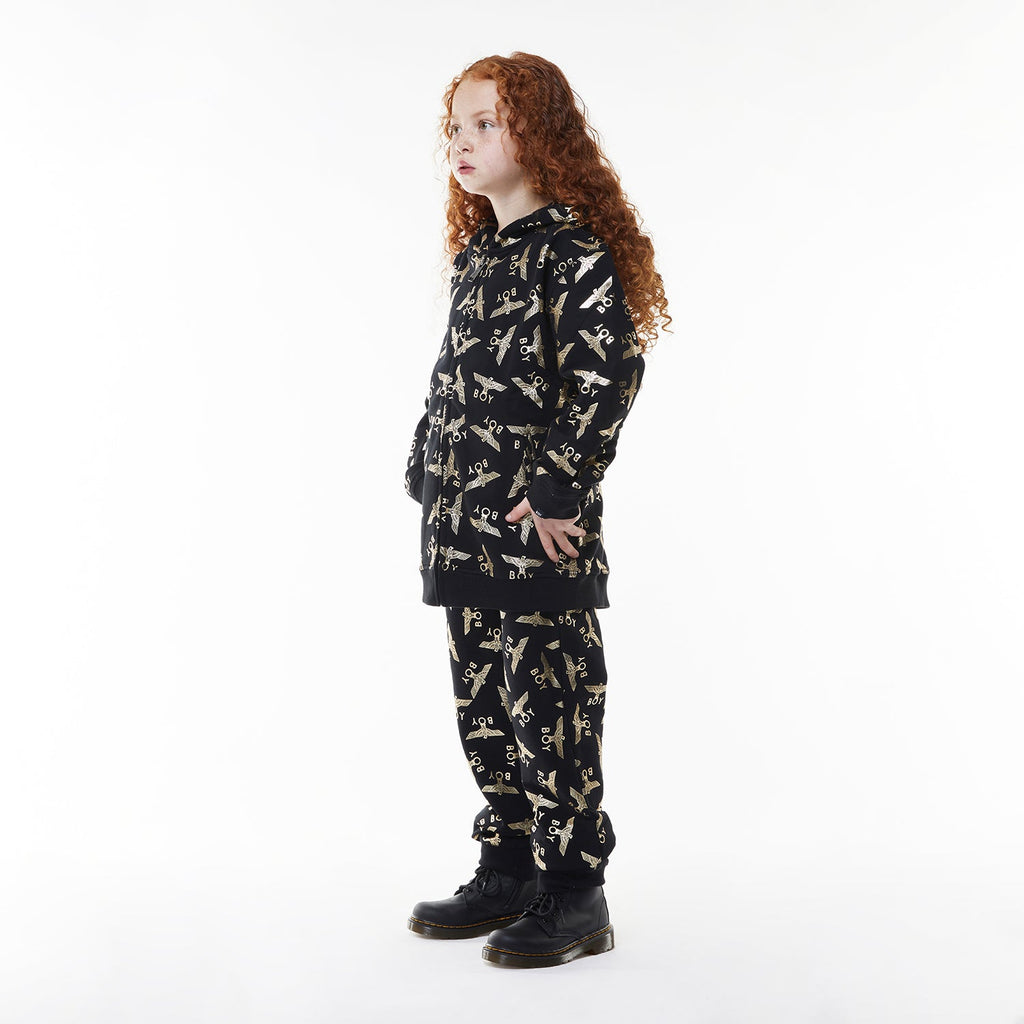 Model wearing Black Boy London pants with yellow airplane pattern on a white background