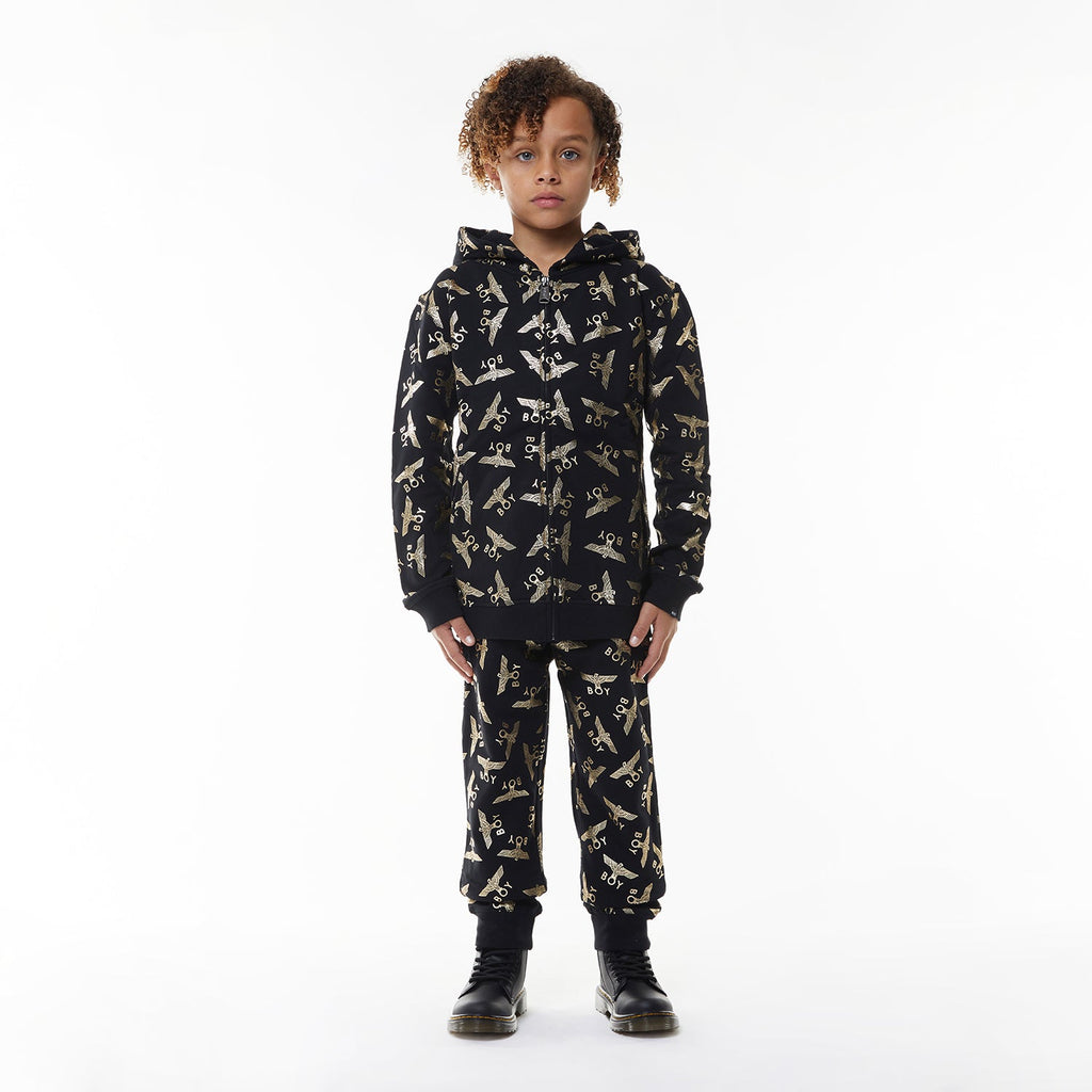 Model wearing Black Boy London pants with yellow airplane pattern on a white background