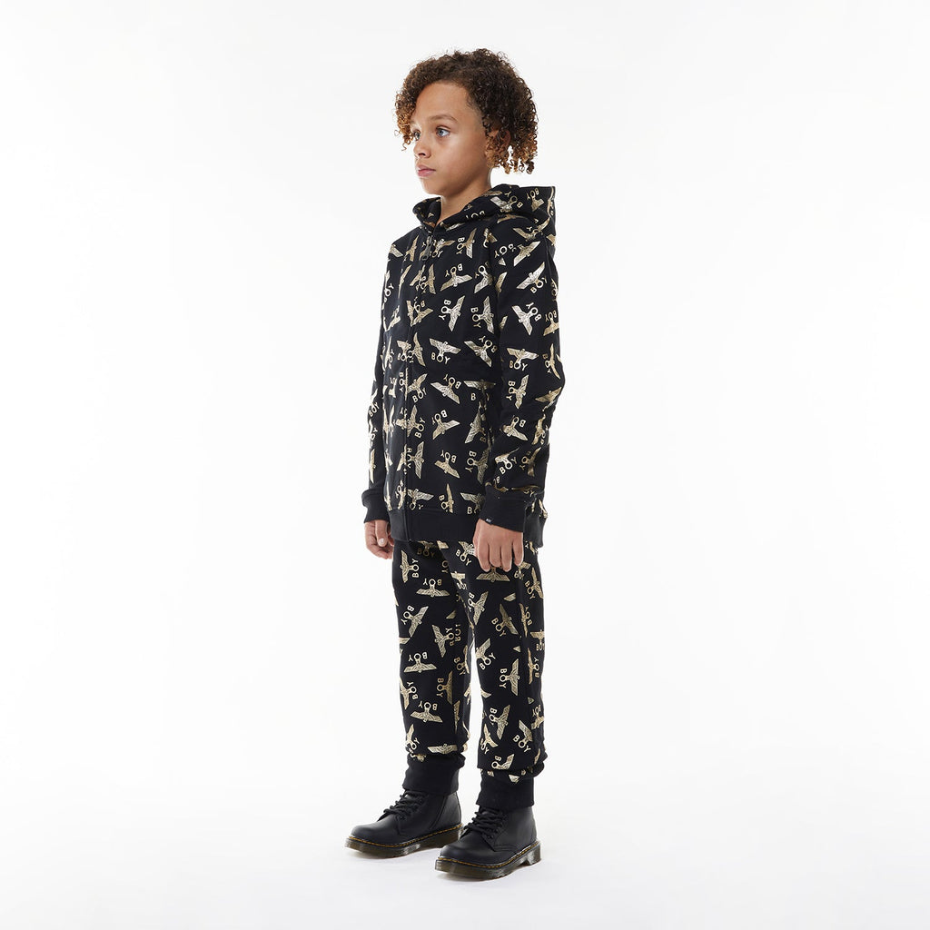 Model wearing Black Boy London pants with yellow airplane pattern on a white background