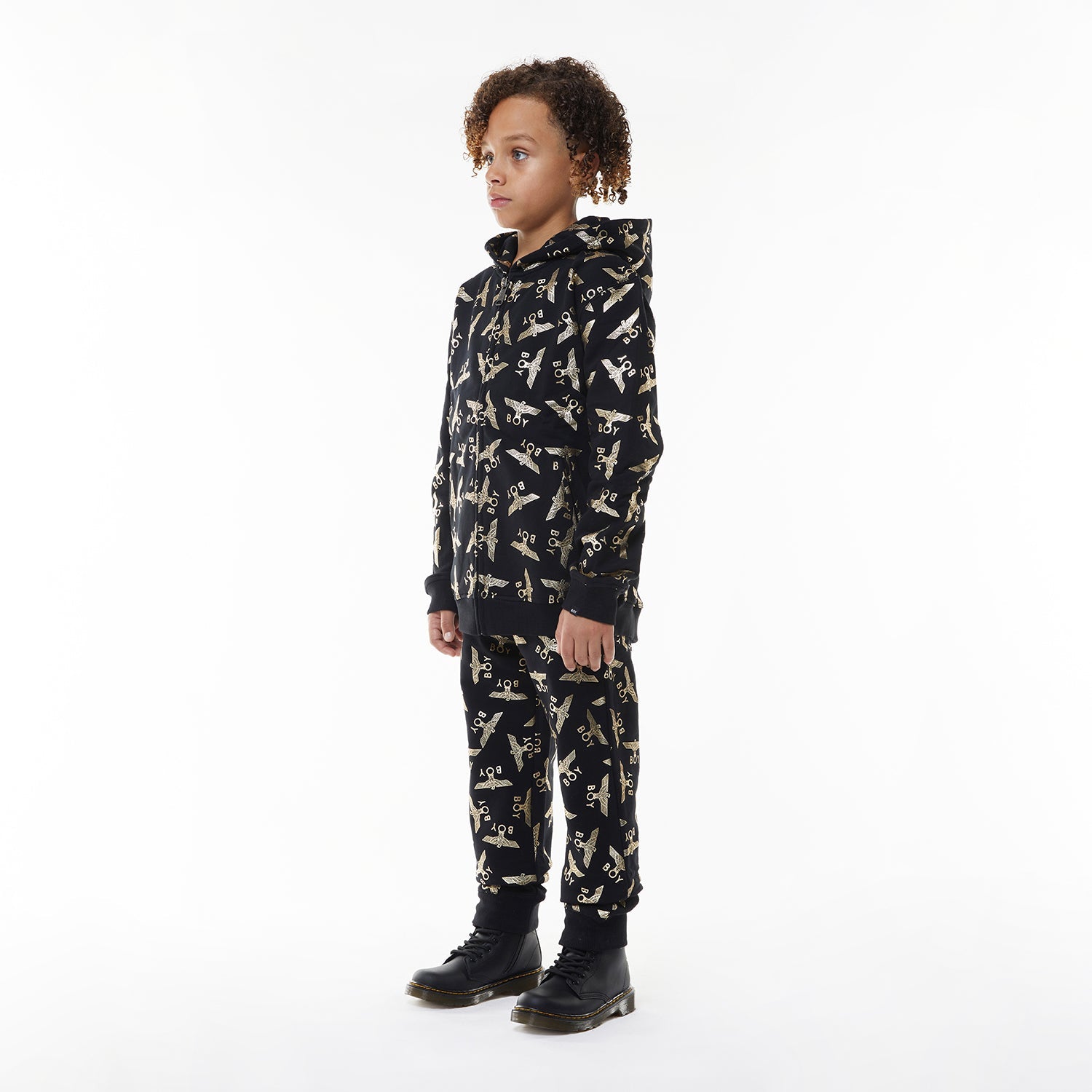 Model wearing Black Boy London pants with yellow airplane pattern on a white background