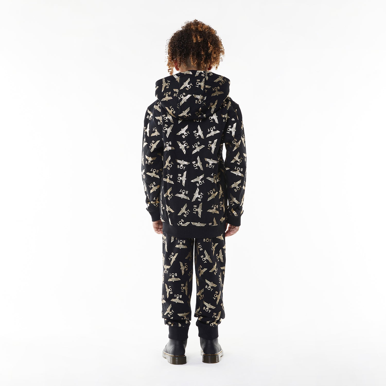 Model wearing Black Boy London pants with yellow airplane pattern on a white background