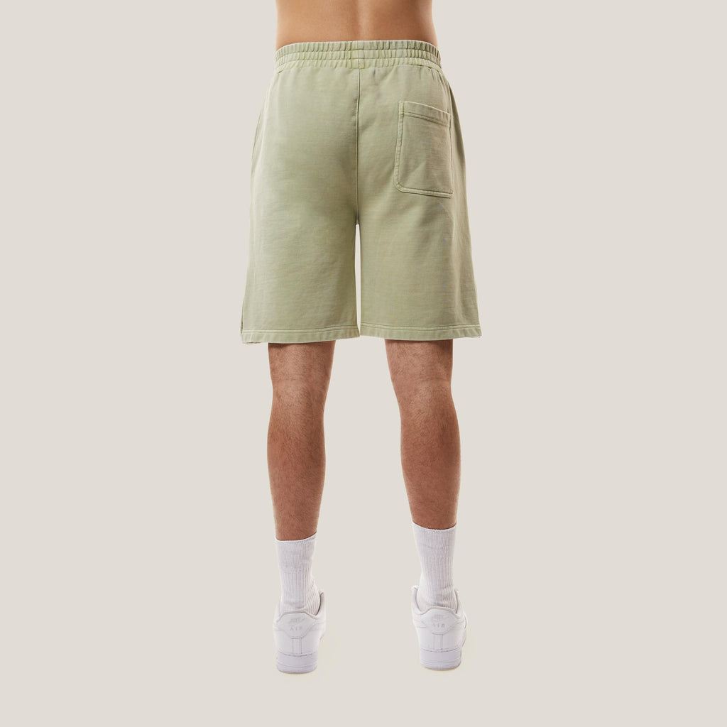 Model wearing Green BOY London shorts with button details on a white background