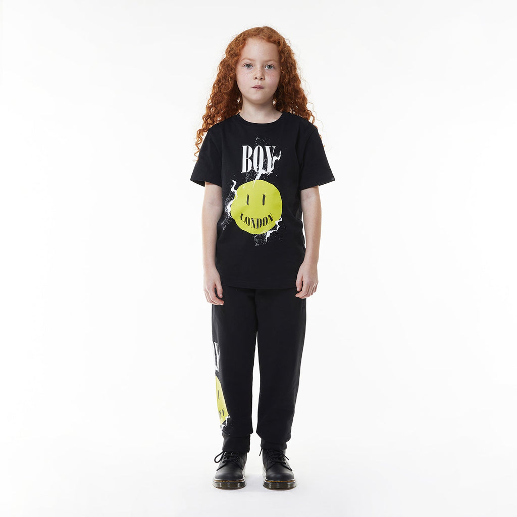 Model wearing Black BOY London t-shirt with yellow smiley face and 'BOY London' text on a white background