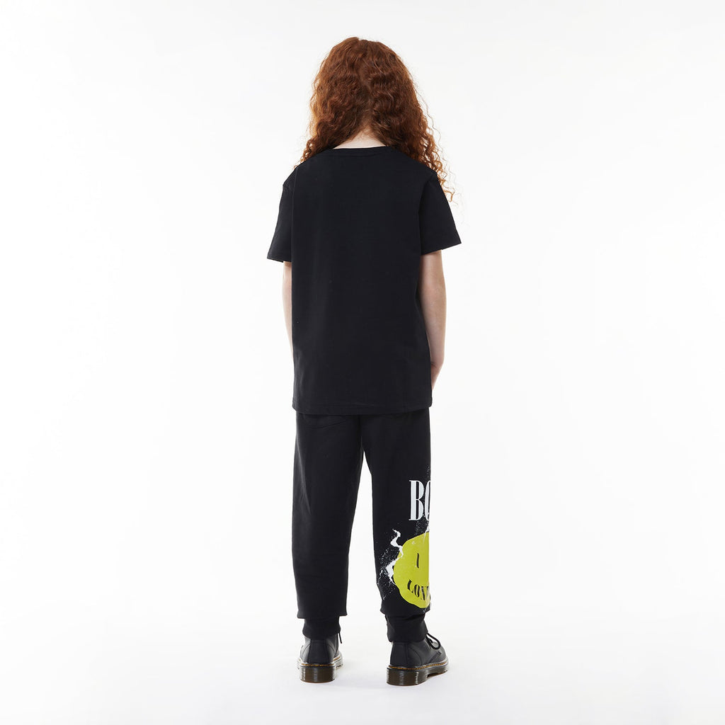 Model wearing Black BOY London t-shirt with yellow smiley face and 'BOY London' text on a white background