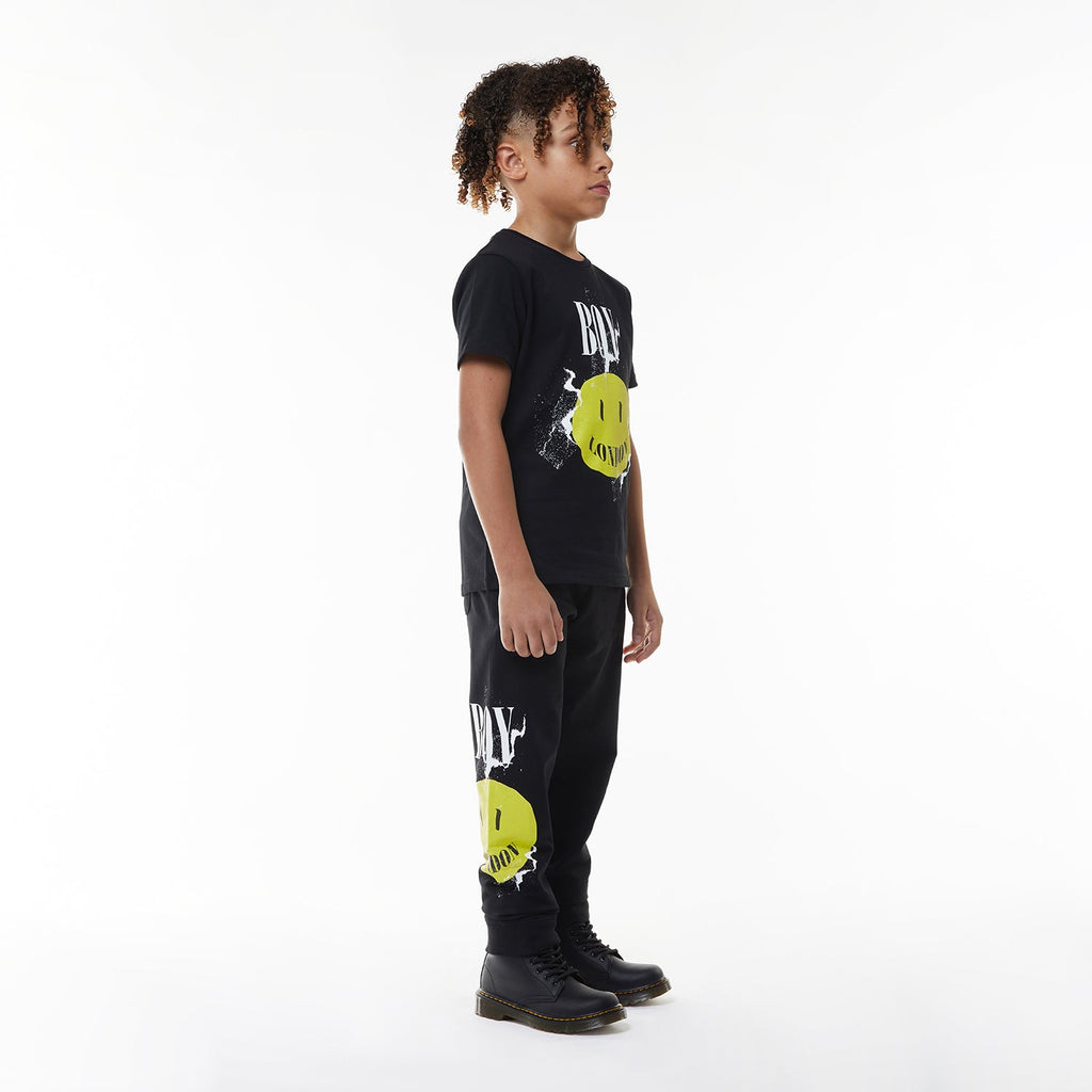 Model wearing Black BOY London t-shirt with yellow smiley face and 'BOY London' text on a white background