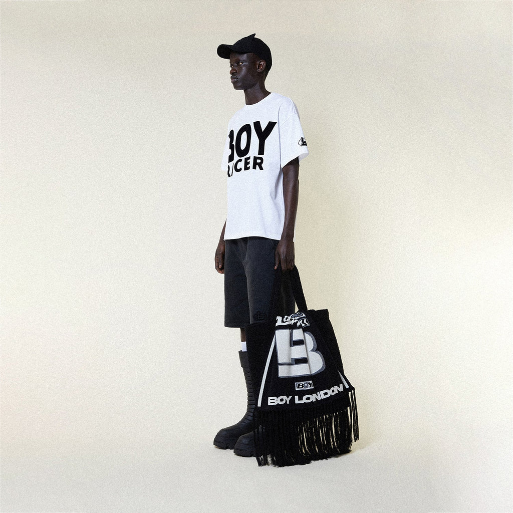 Person wearing a BOY LONDON white t-shirt with 'BOY RACER' text, black shorts, and black boots on a plain background