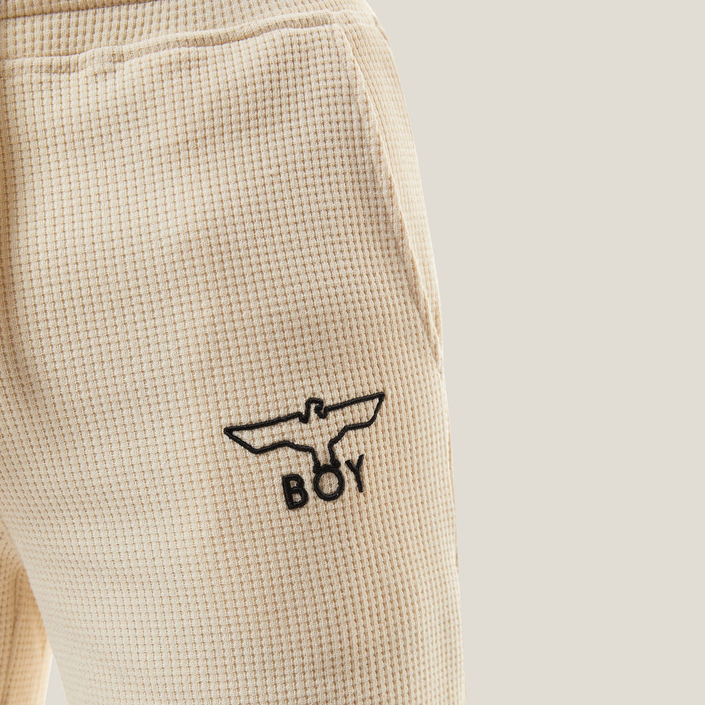 Model wearing BOY London Beige shorts with a logo on a white background