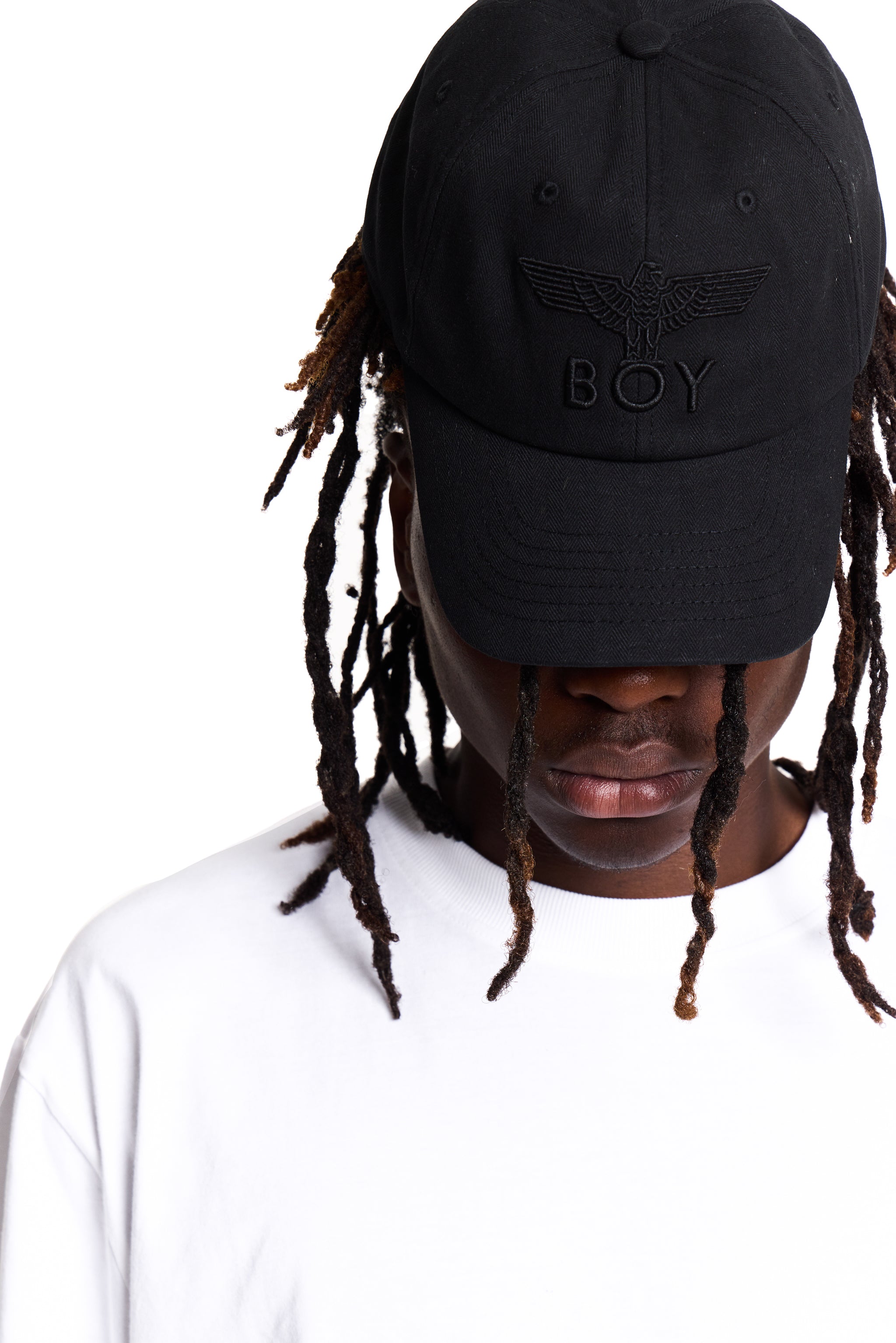 Person wearing a black cap with 'BOY' London 