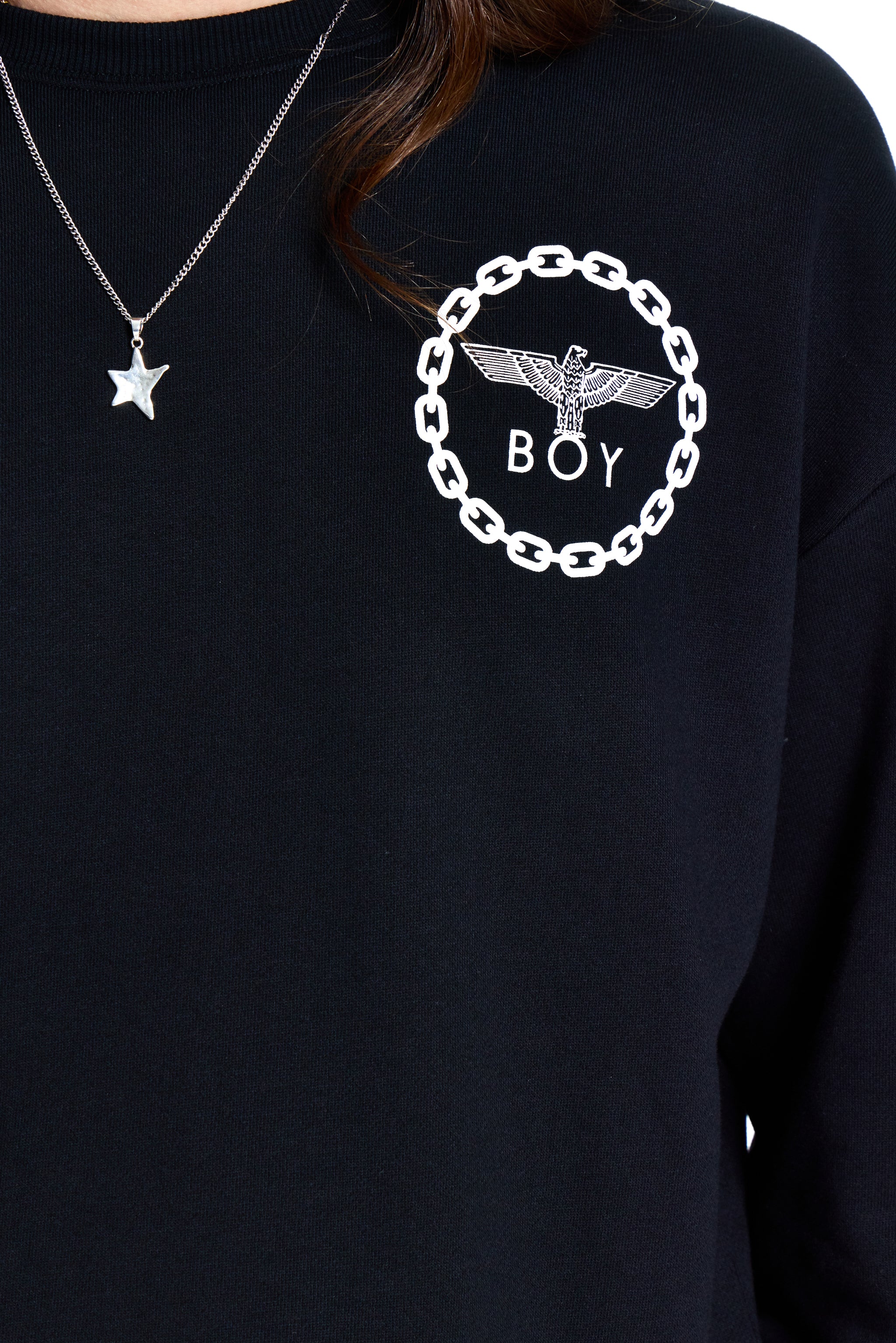Black sweatshirt with 'BOY' logo and chain design, worn by a person.
