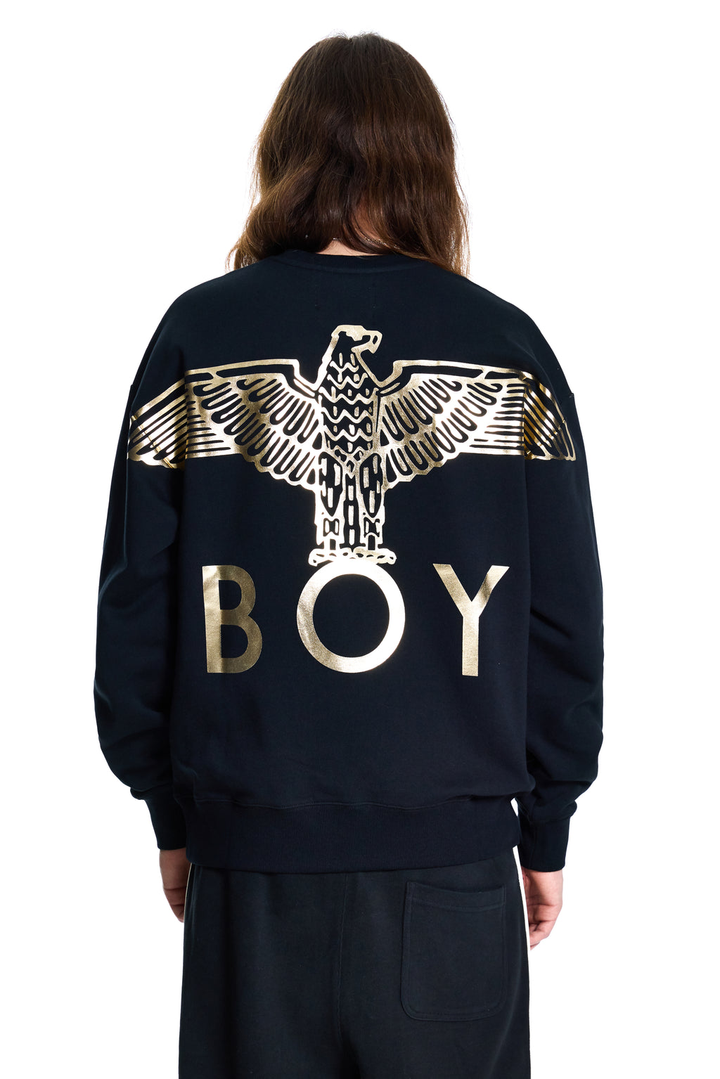 Person wearing a black Boy London sweatshirt with a gold eagle design and 'BOY' text on the back.