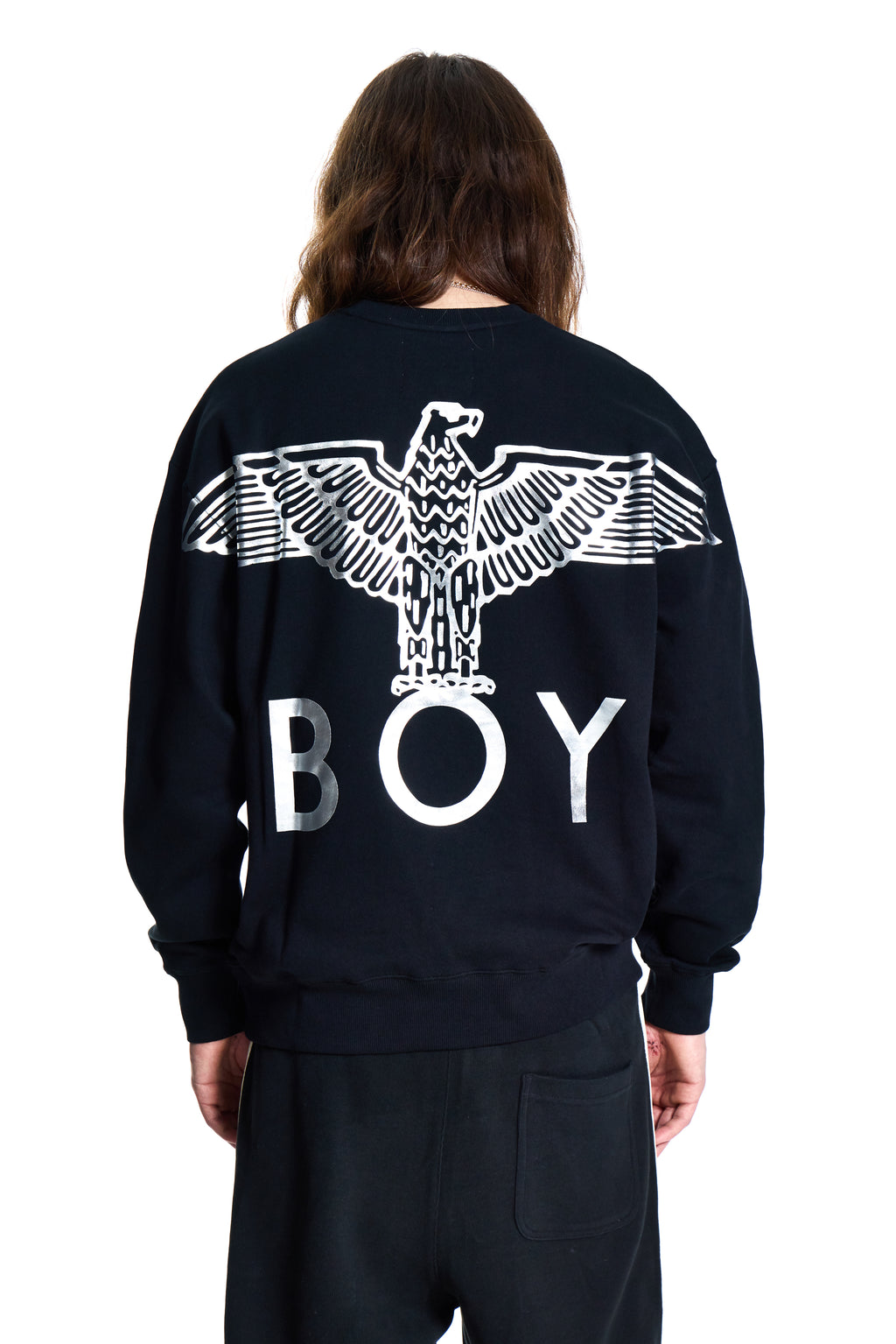 Person wearing a black Boy London  sweatshirt with an eagle design and 'BOY' text on the back, standing against a white background.
