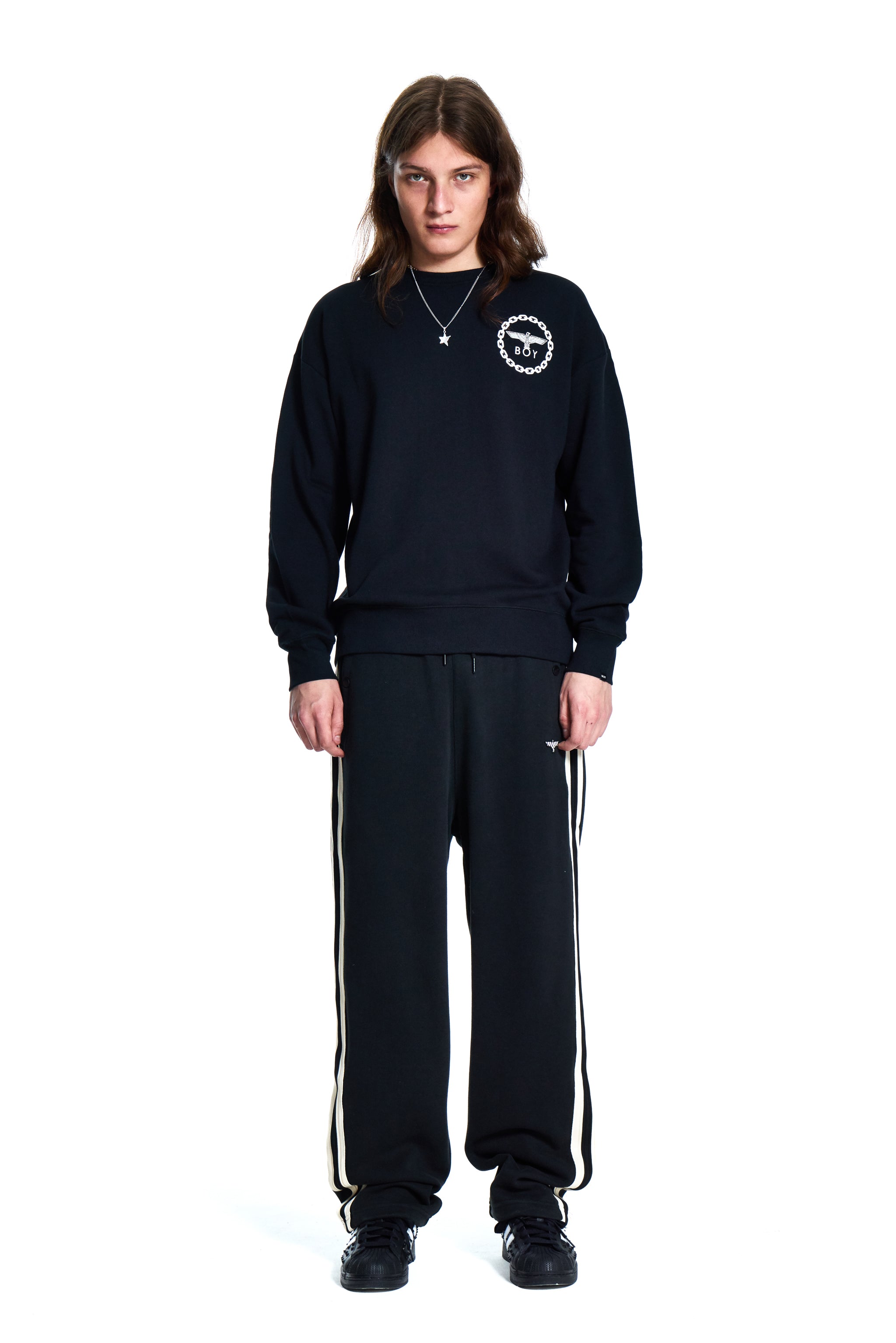 Person wearing a black Boy London tracksuit with a logo on a white background