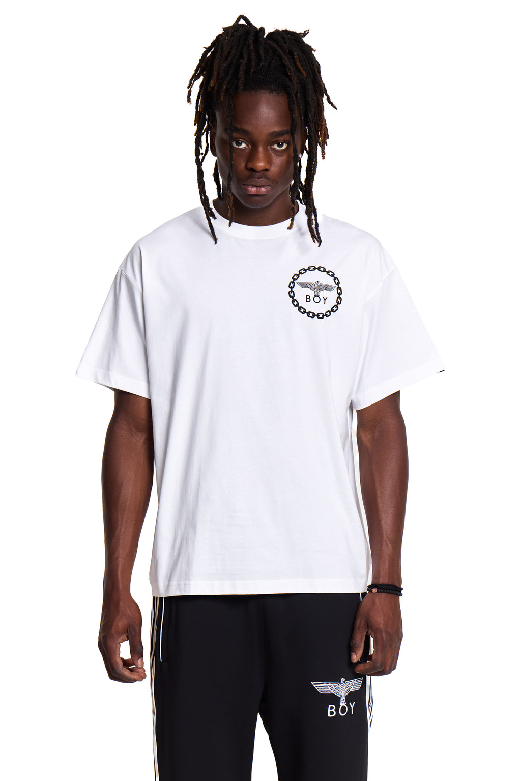 Model wearing a white BOY London t-shirt with a logo and black pants with branding on a white background