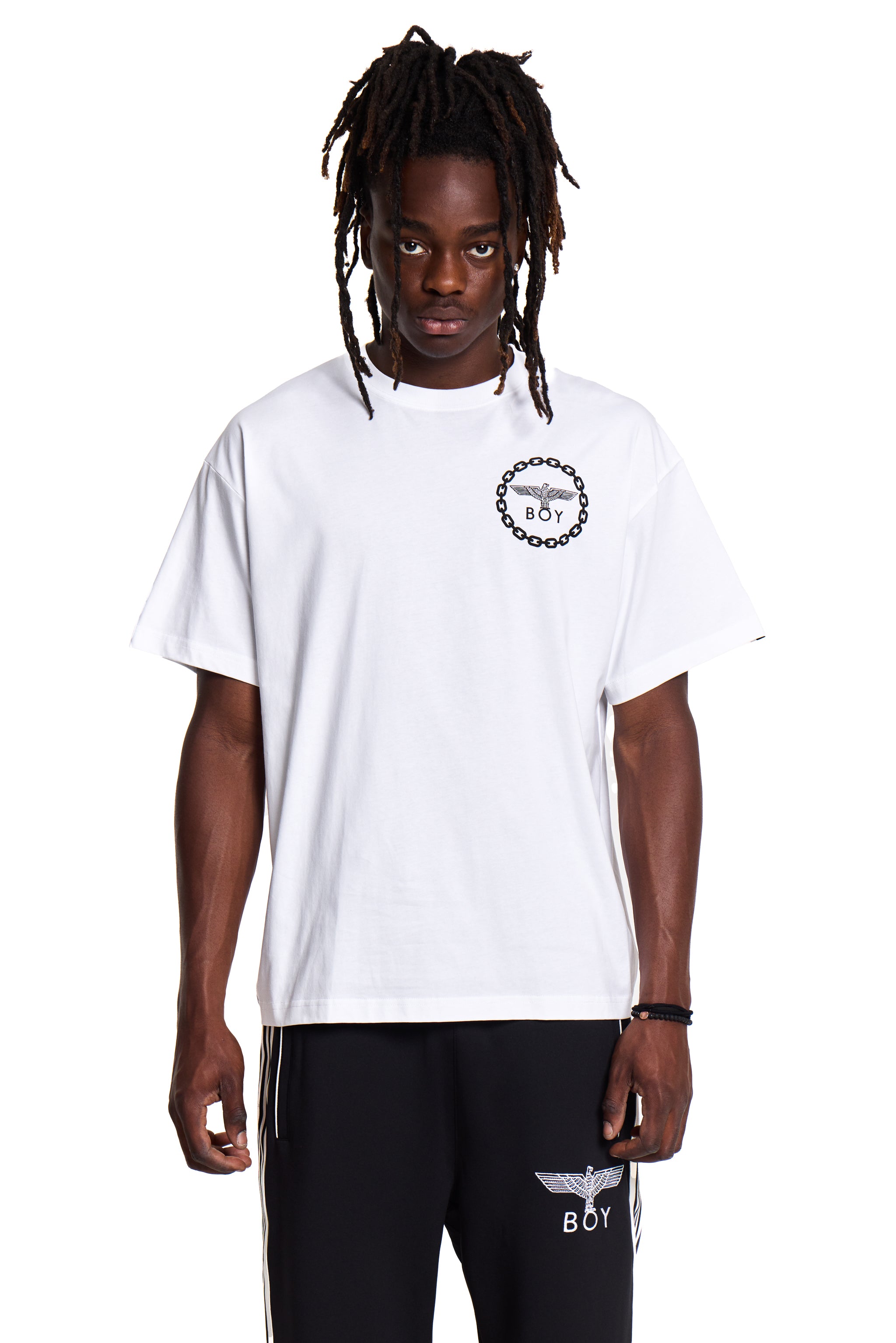 Model wearing a white BOY London t-shirt with a logo and black pants with branding on a white background