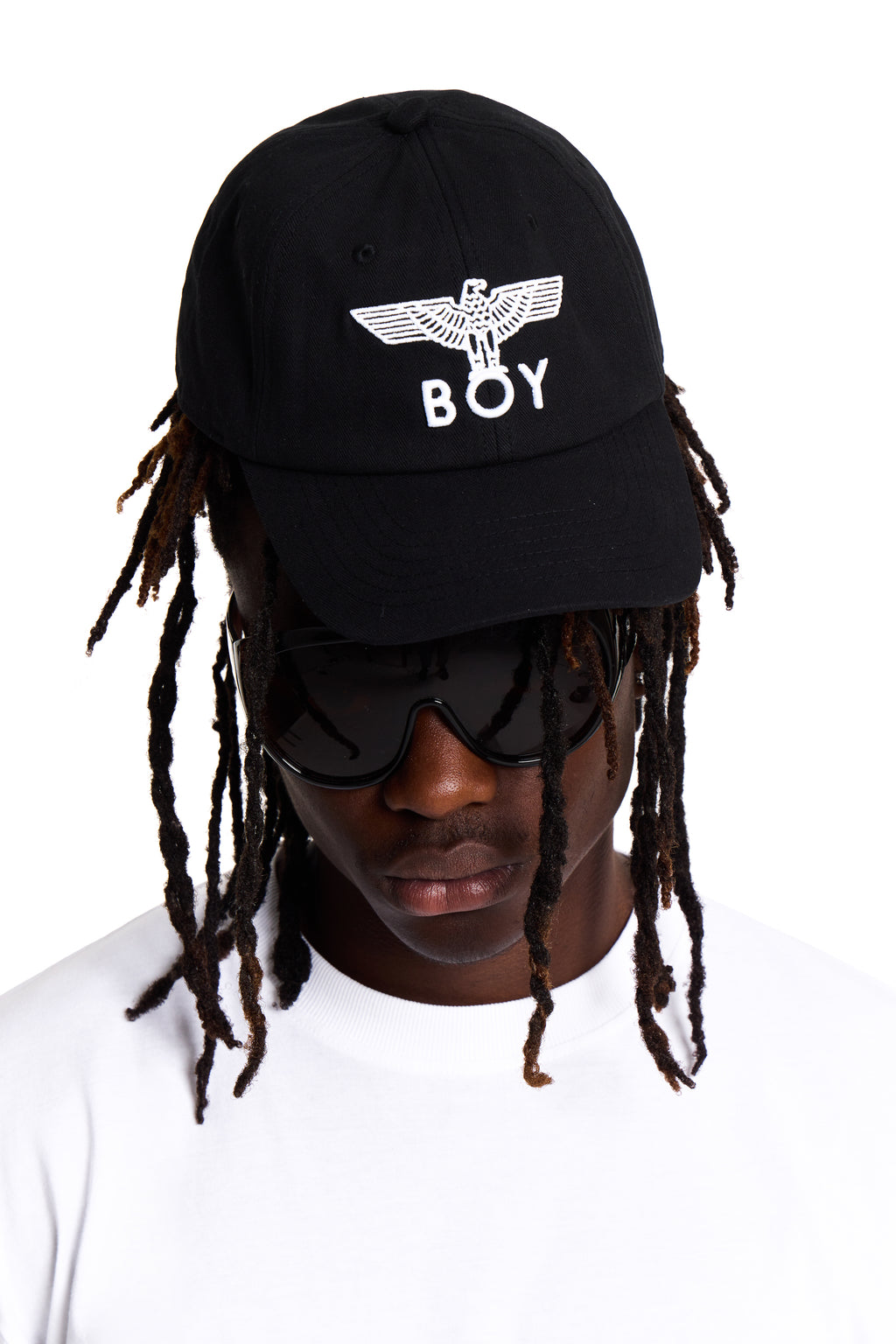 Person wearing a black cap with 'BOY' LONDON logo and sunglasses on a white background