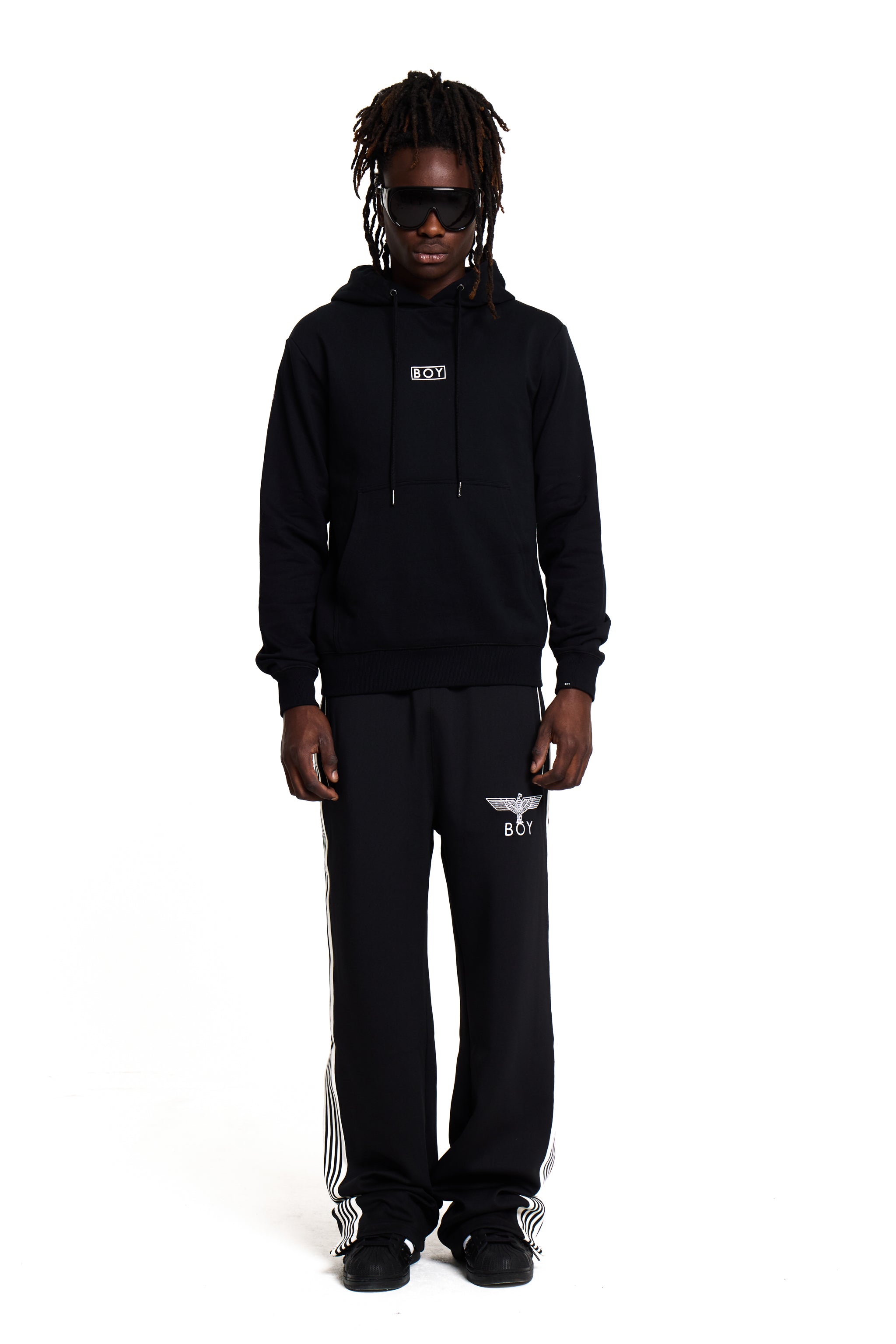 Model wearing a black BOY London tracksuit with brand logos on a white background