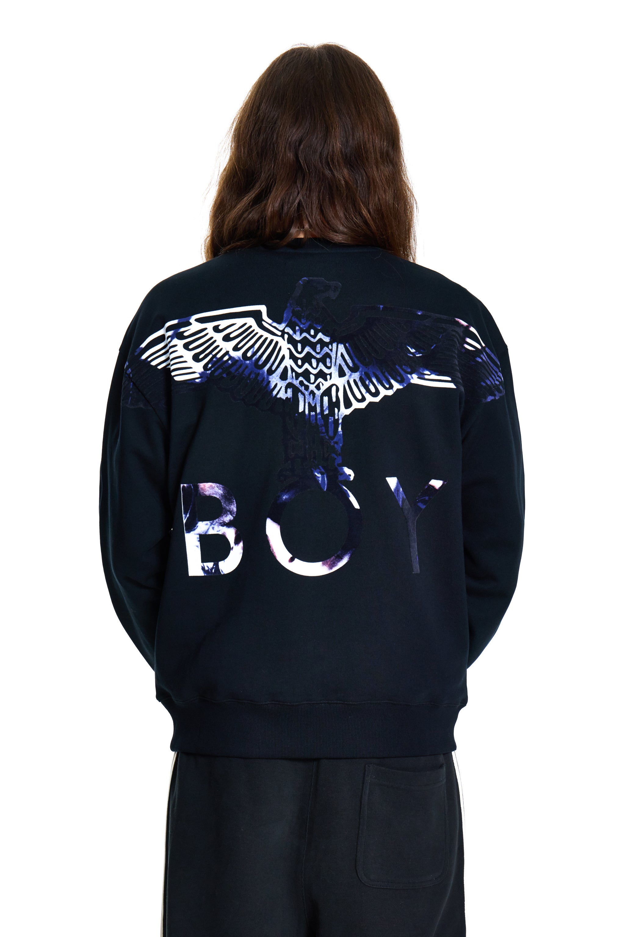 Person wearing a dark blue hoodie with a reflective design on the back, standing against a white background.