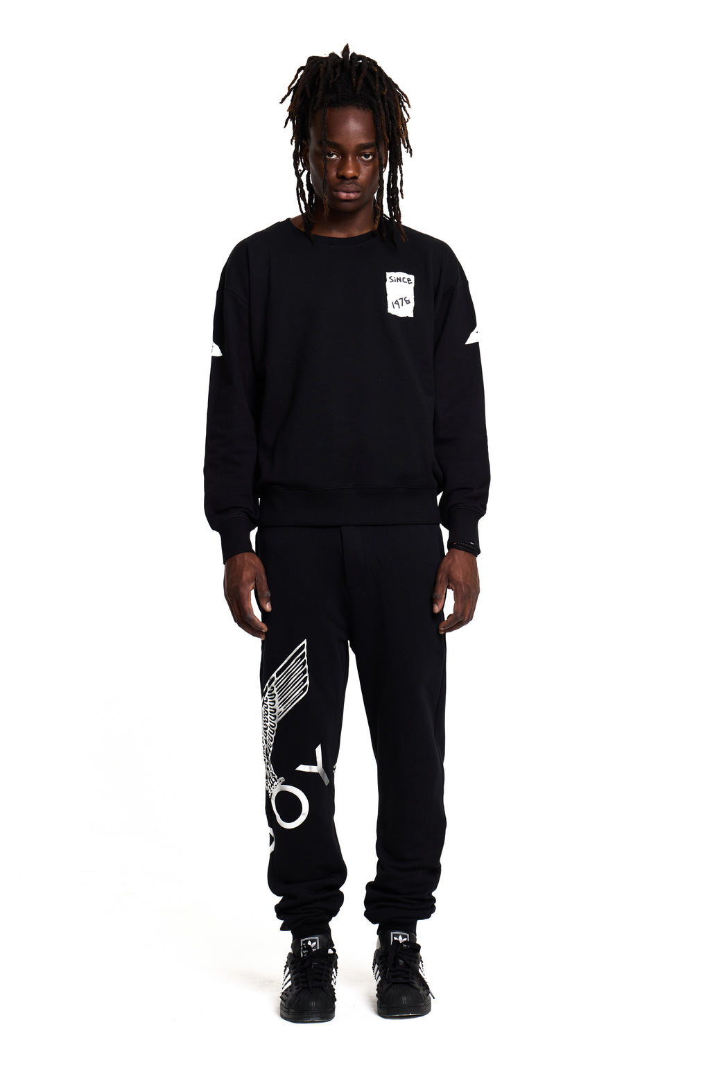 Model wearing a black BOY London sweatshirt and pants with white text on a white background