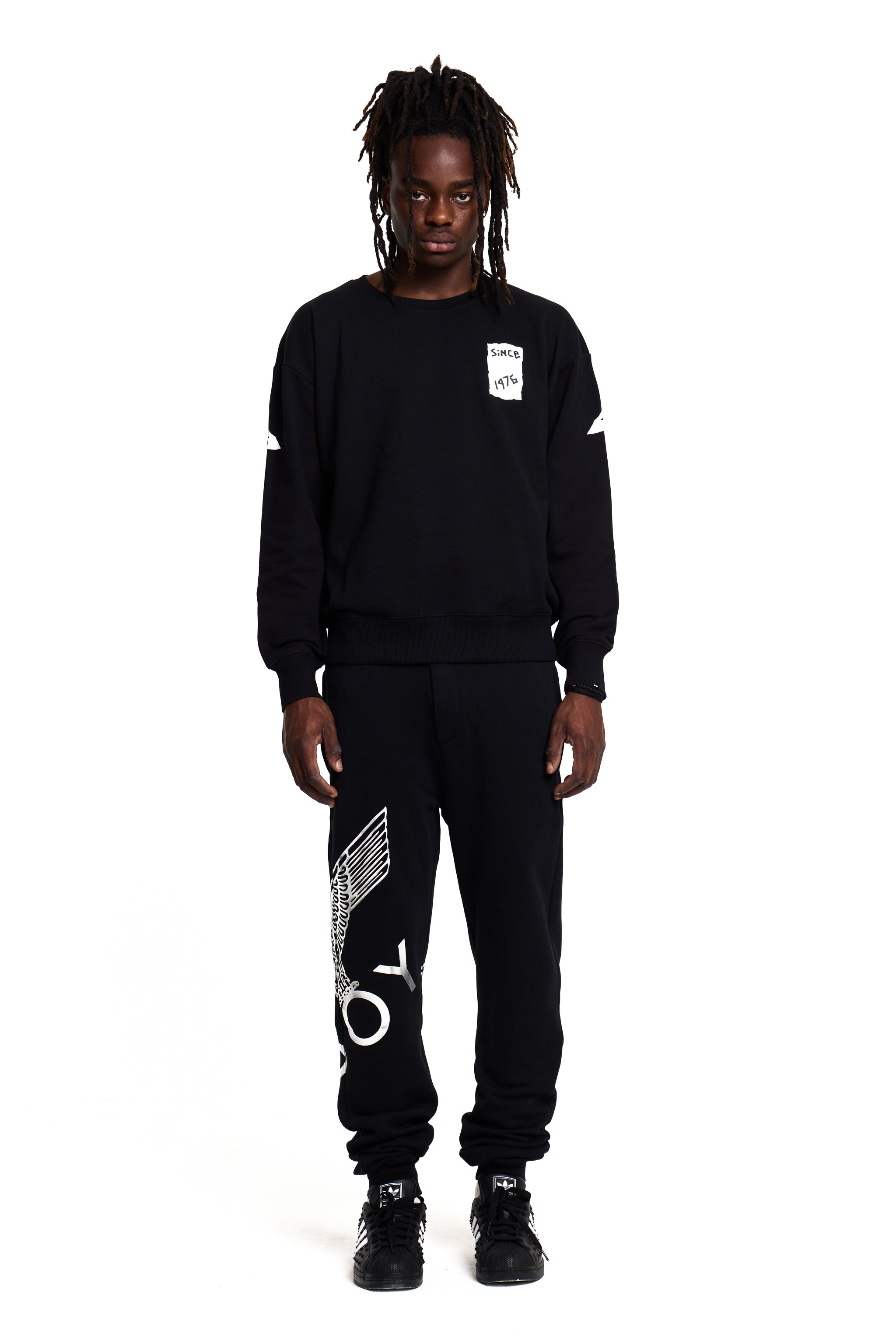 Model wearing a black BOY London sweatshirt and pants with white text on a white background