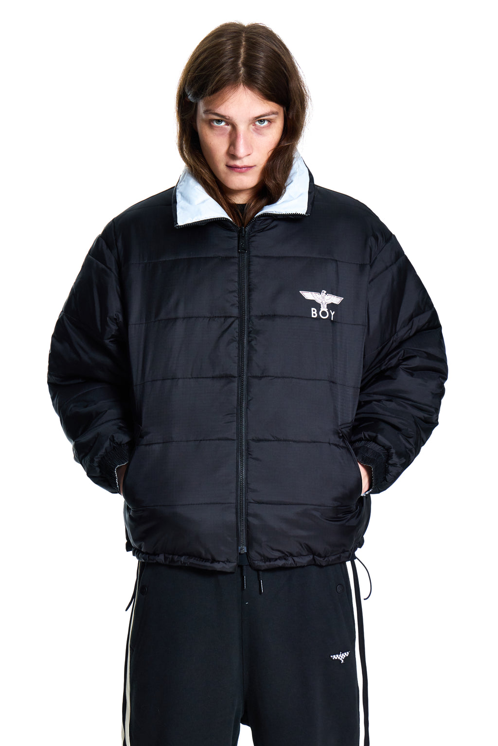 Person wearing a black puffer jacket with a white logo on a white background