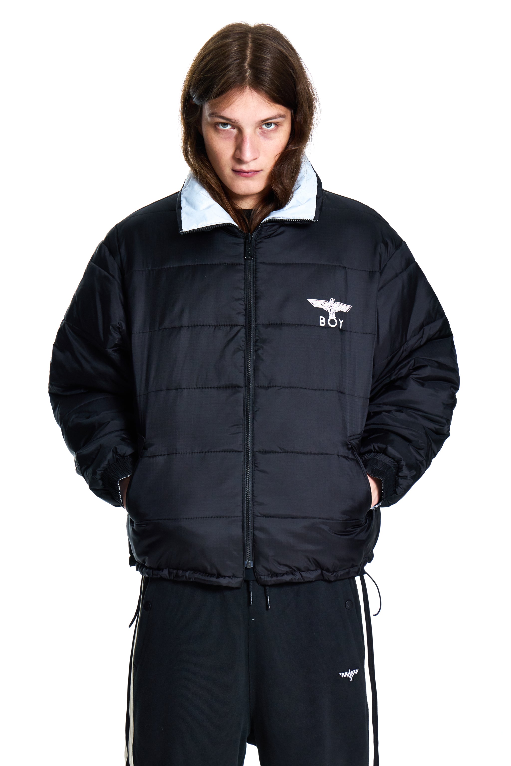 Person wearing a black puffer jacket with a white logo on a white background