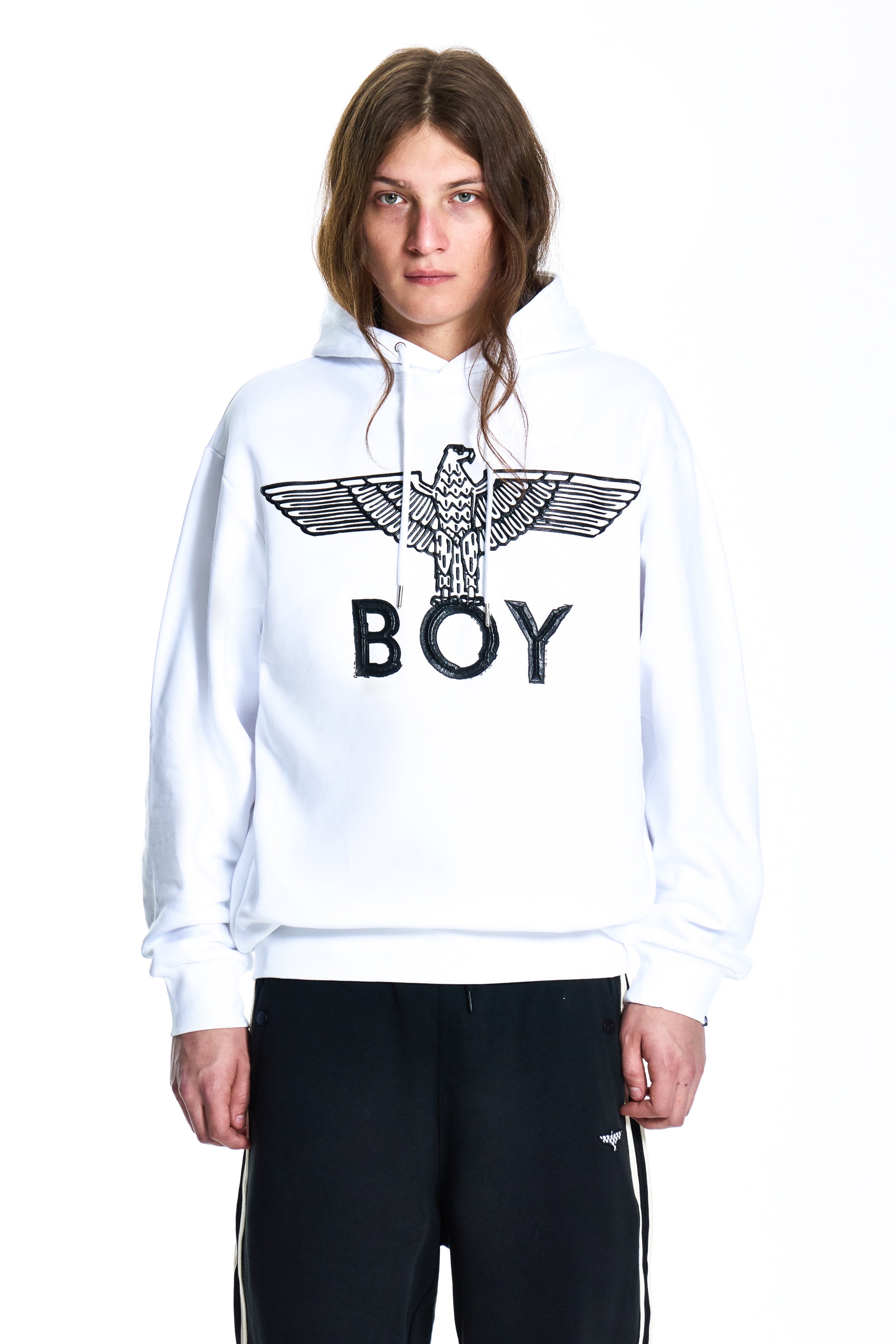Person wearing a white hoodie with a logo and text, standing against a white background