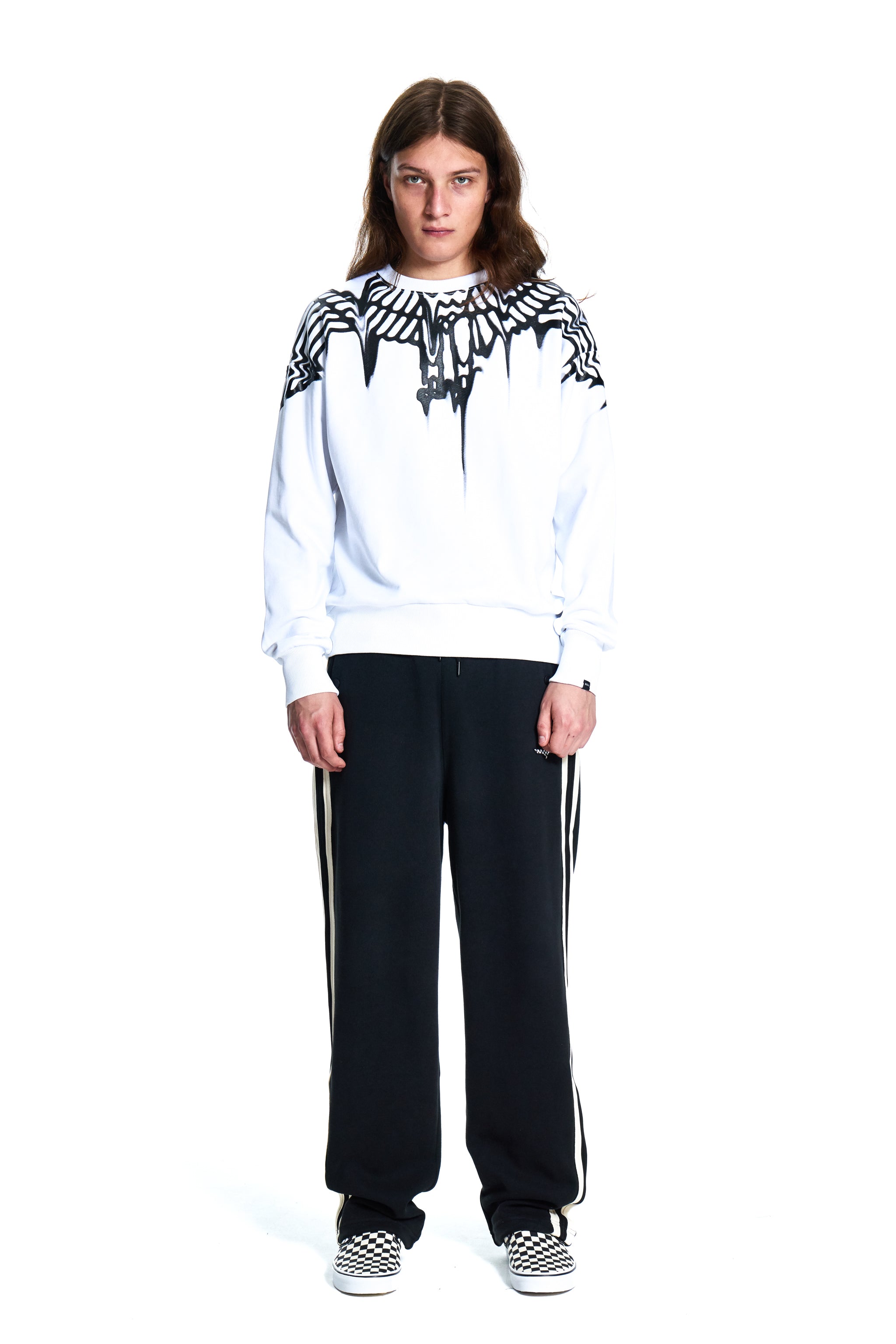 Person wearing a white Boy London hoodie with black and white patterned design and black pants with white stripes on a white background