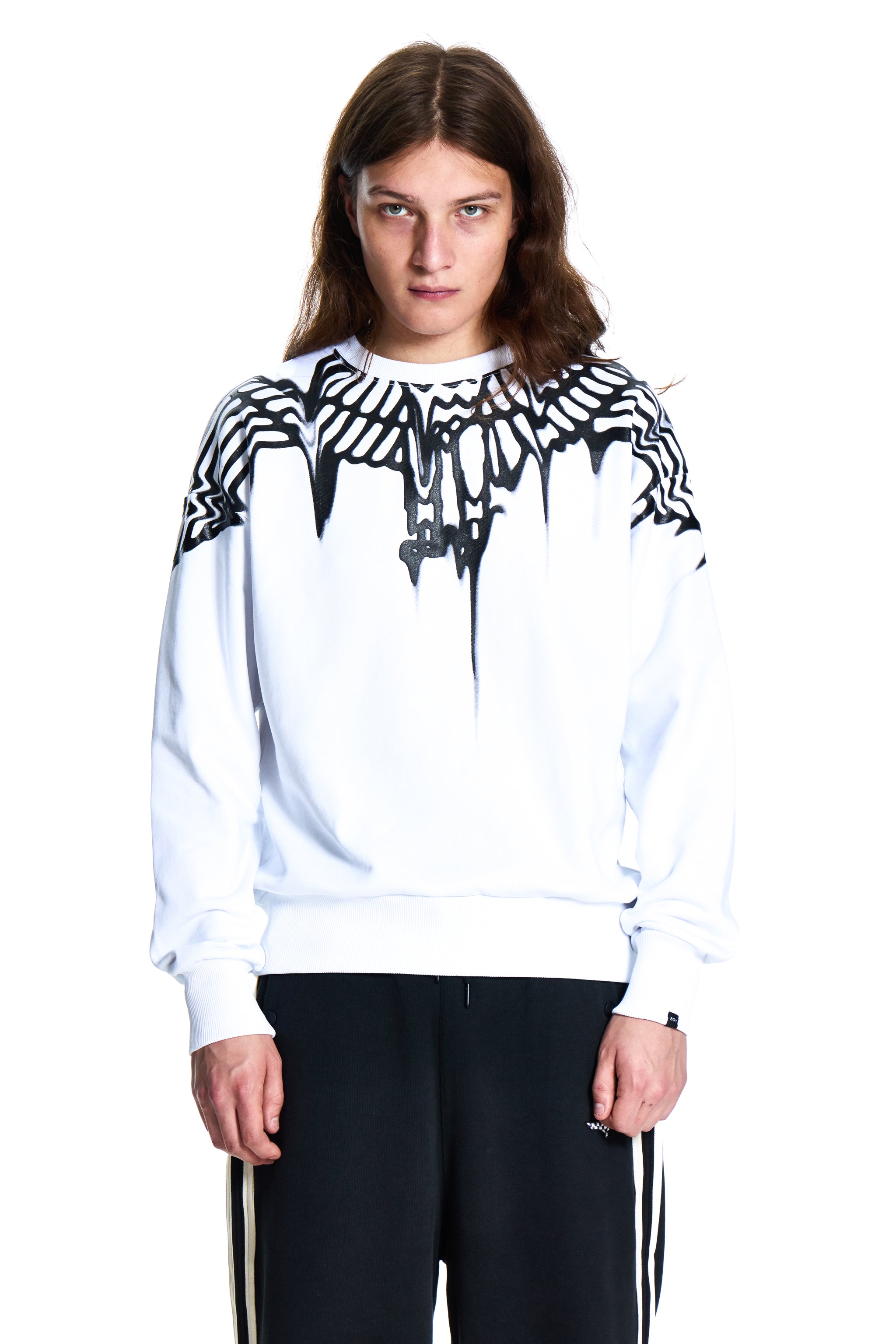 Person wearing a white Boy London sweatshirt with black graphic design on a white background