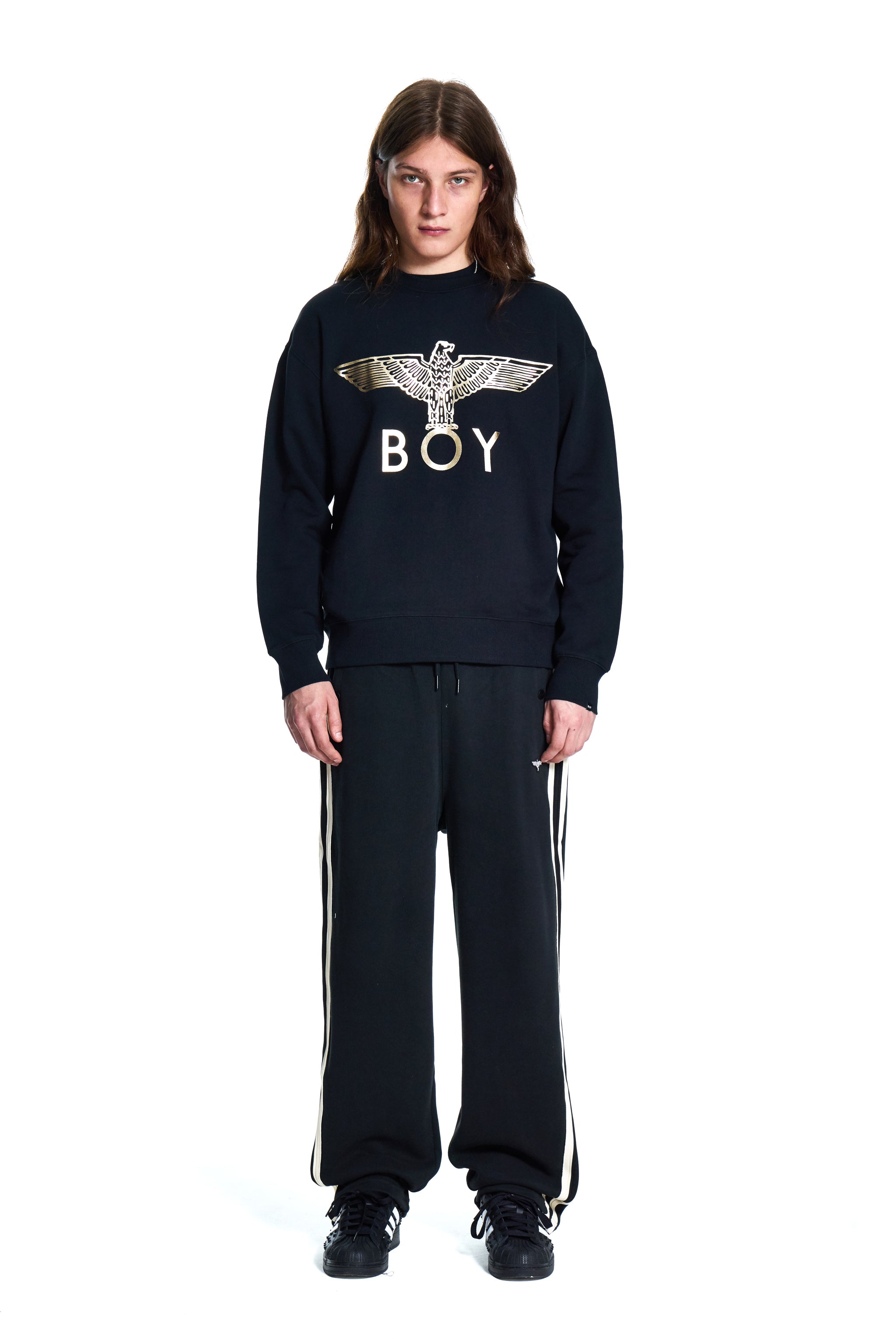 Person wearing a black Boy London sweatshirt with 'BOY' logo and black pants on a white background