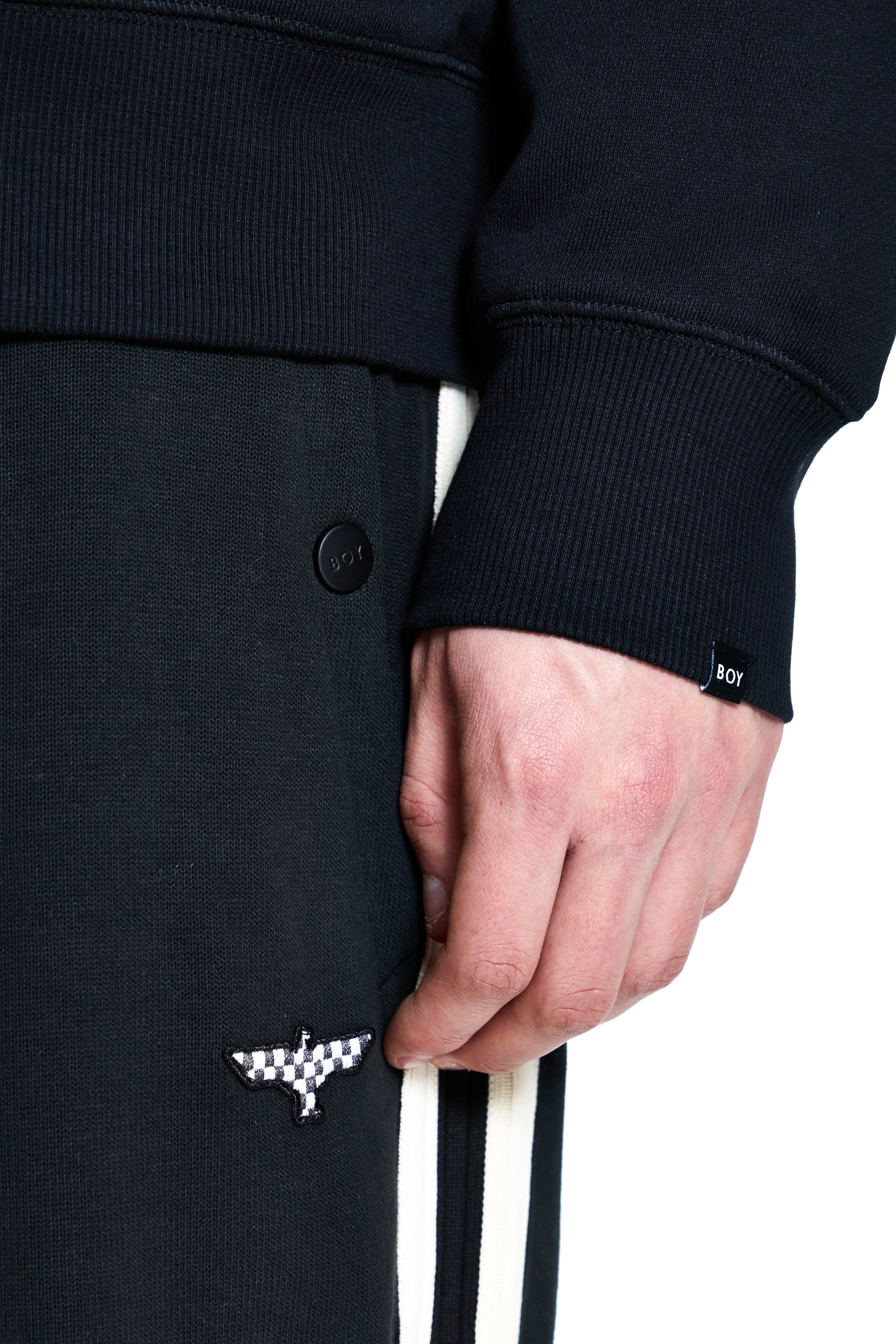Close-up of a person wearing a black coat with a brand logo on a white background