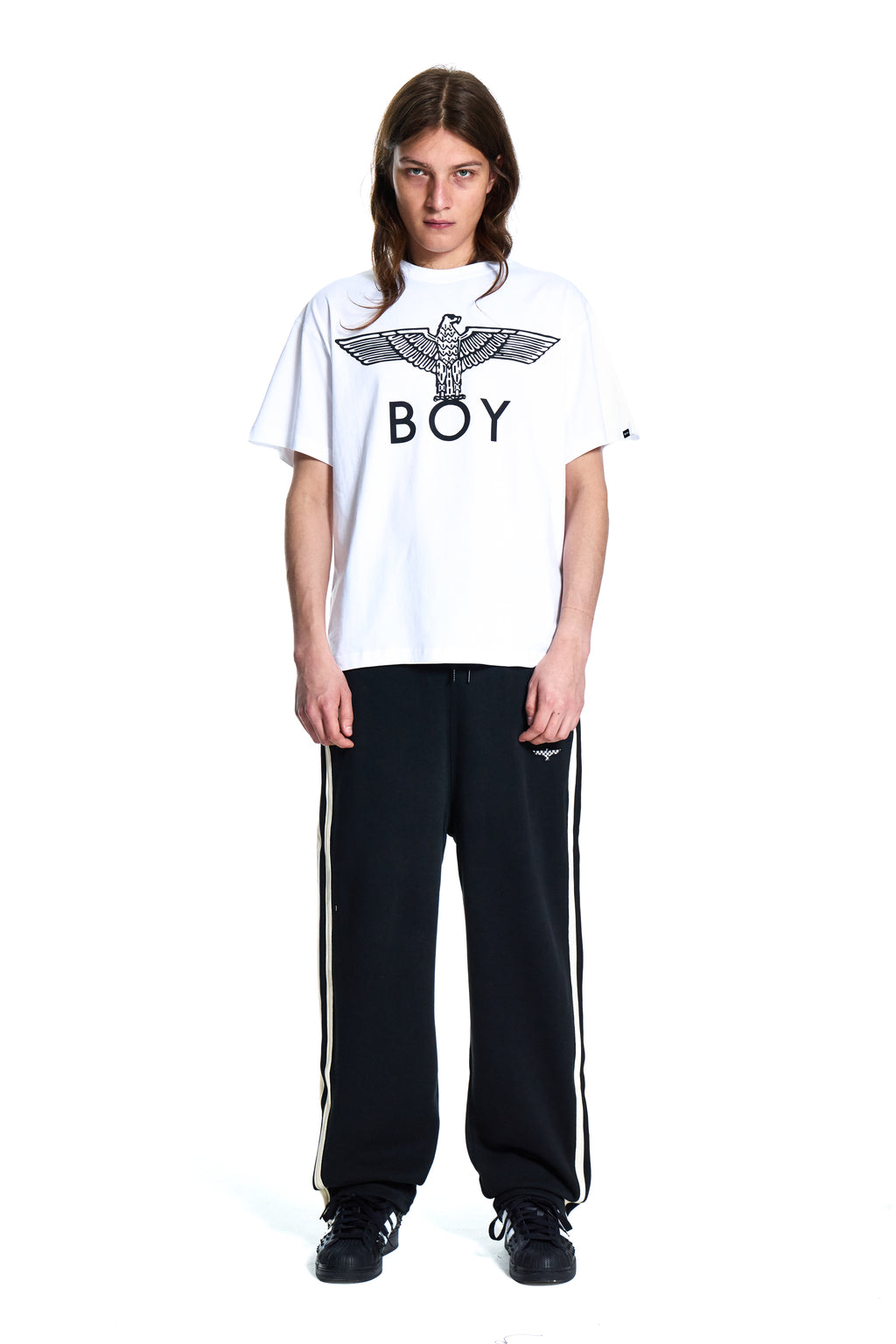 Person wearing a white t-shirt with a logo and black pants on a white background