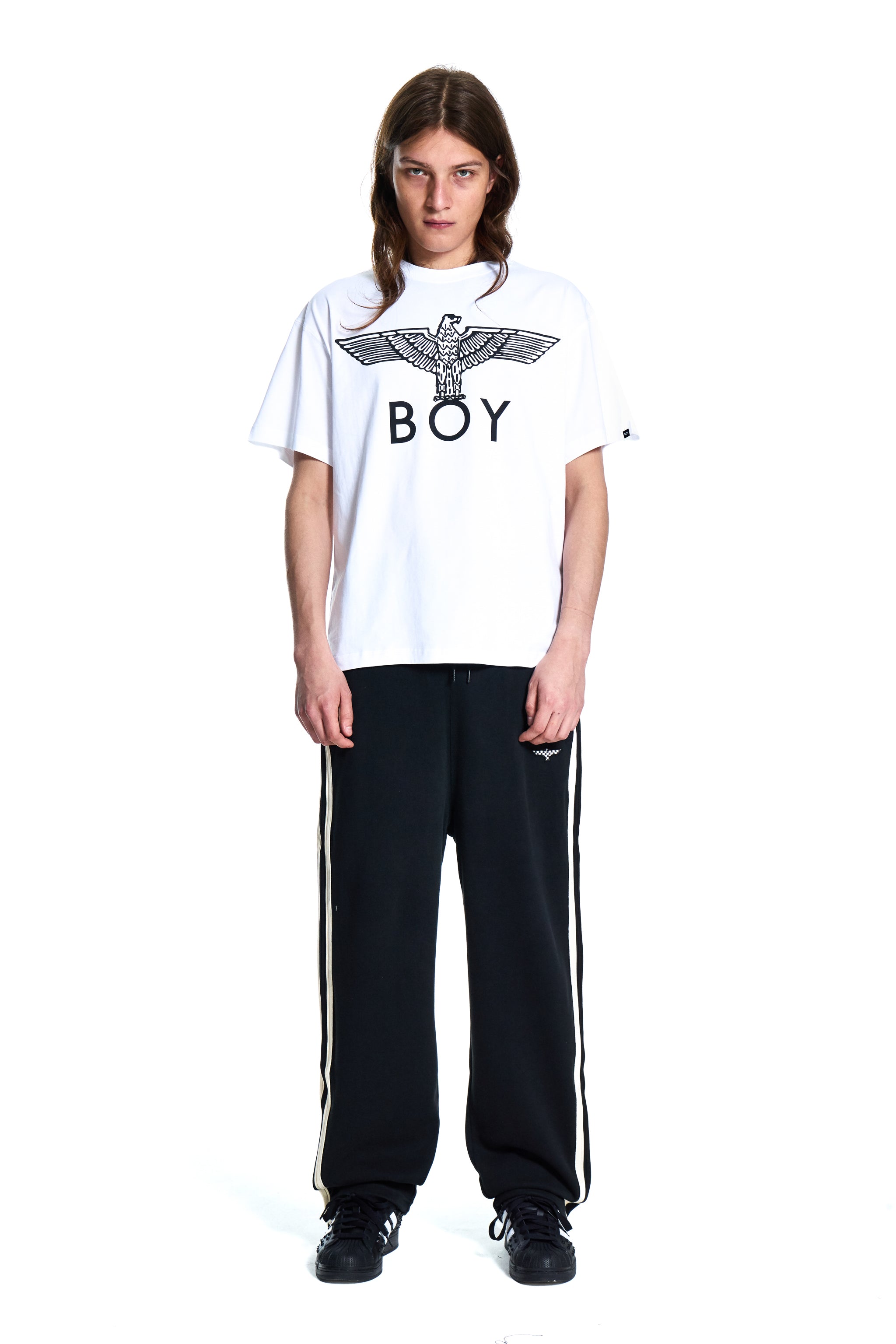 Person wearing a white t-shirt with a logo and black pants on a white background