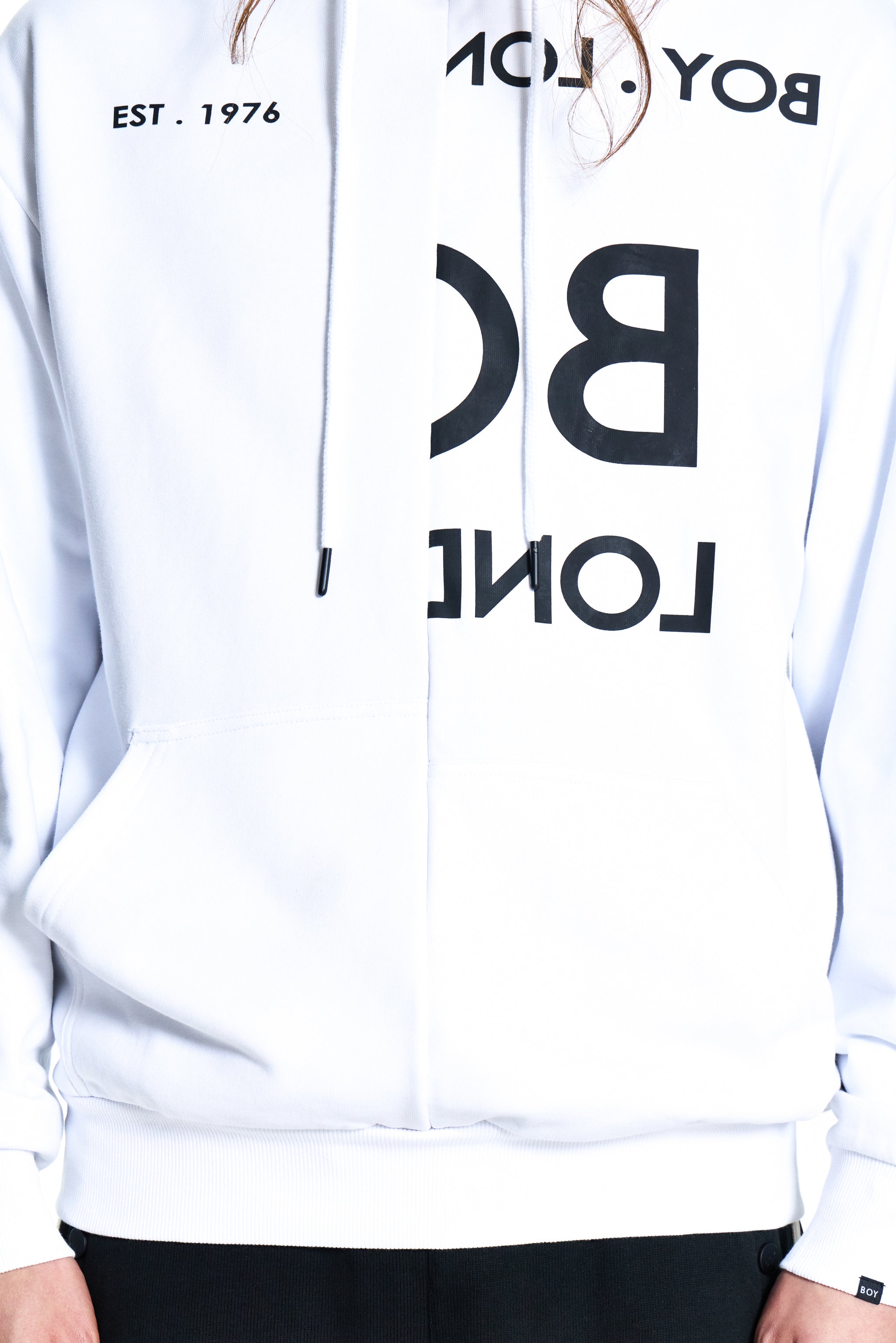 White hoodie with black text and branding on a person wearing it.