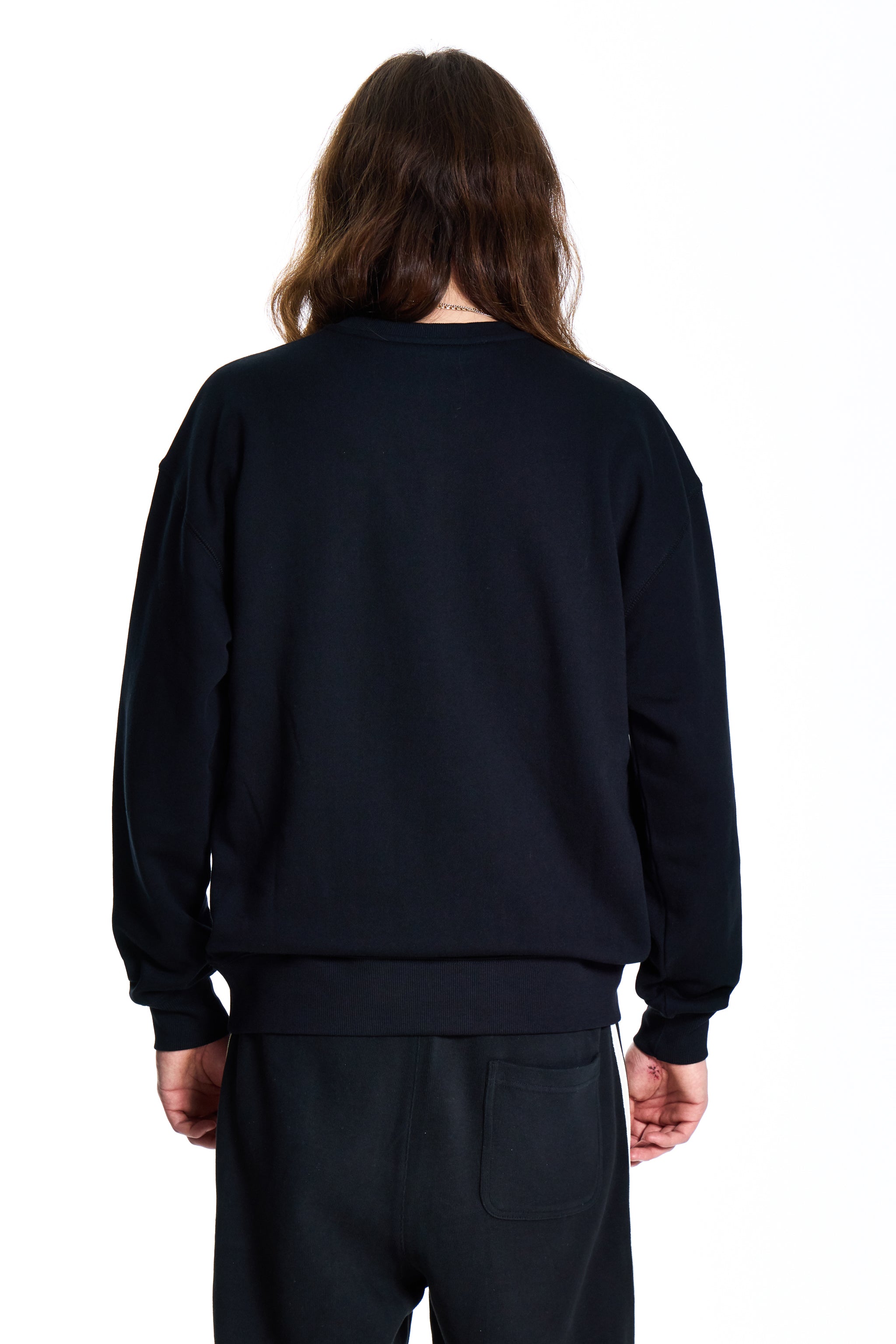 Person wearing a black sweatshirt and pants on a white background