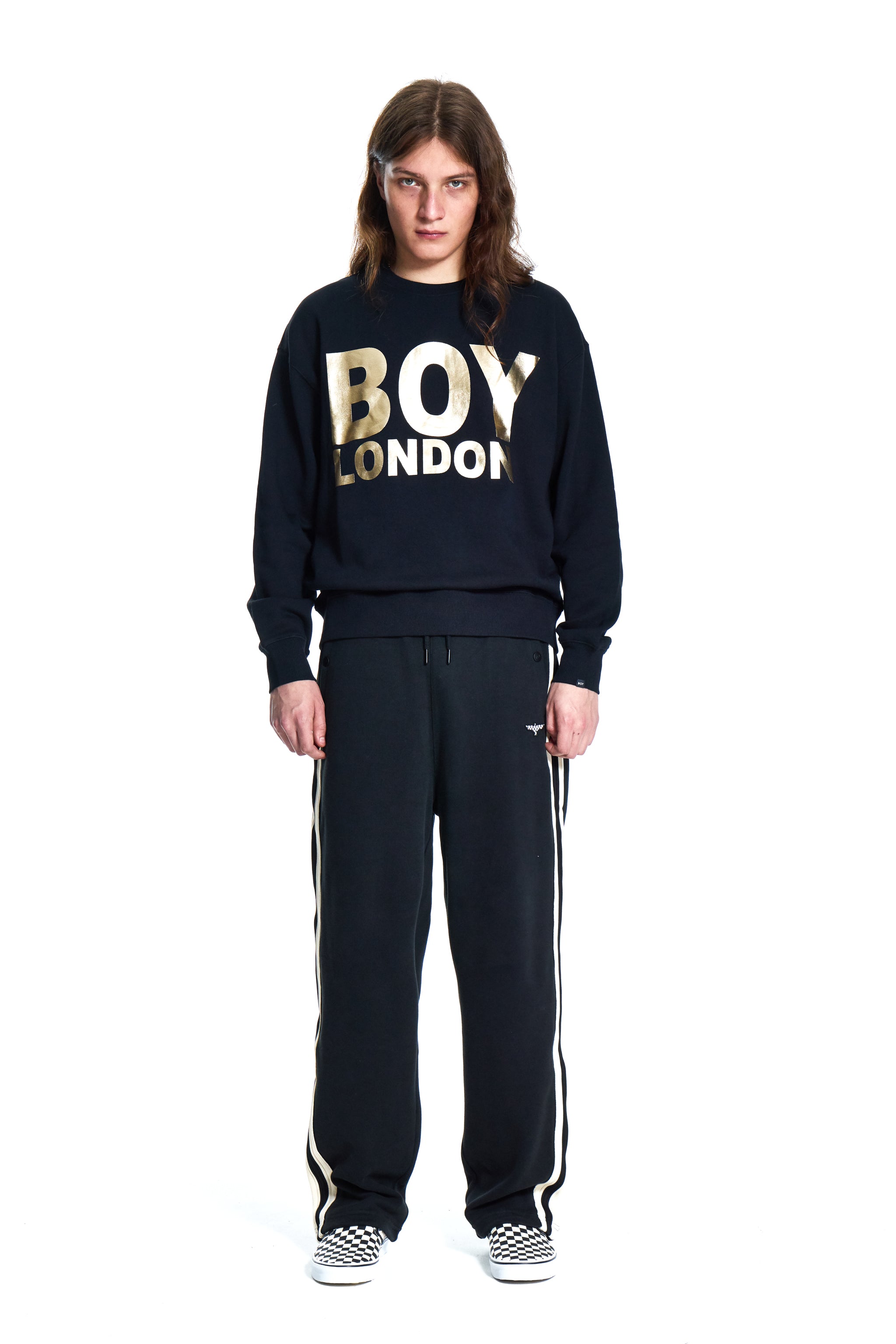 Person wearing a black 'BOY LONDON' sweatshirt and pants on a white background