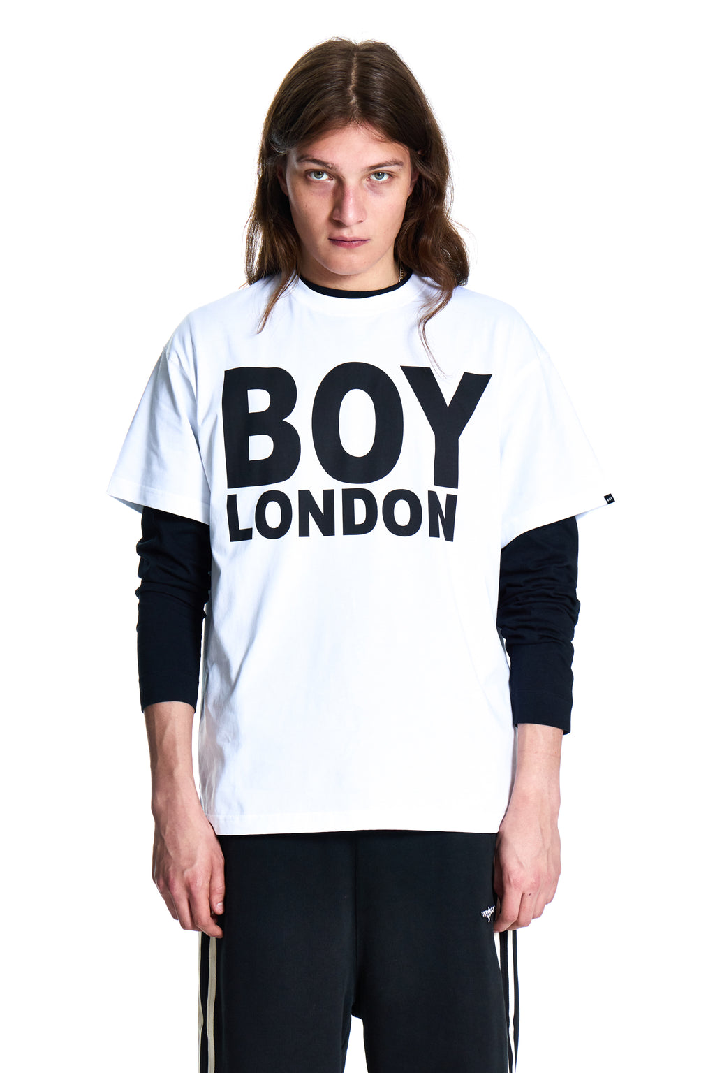 Person wearing a white 'BOY LONDON' shirt with black sleeves on a white background