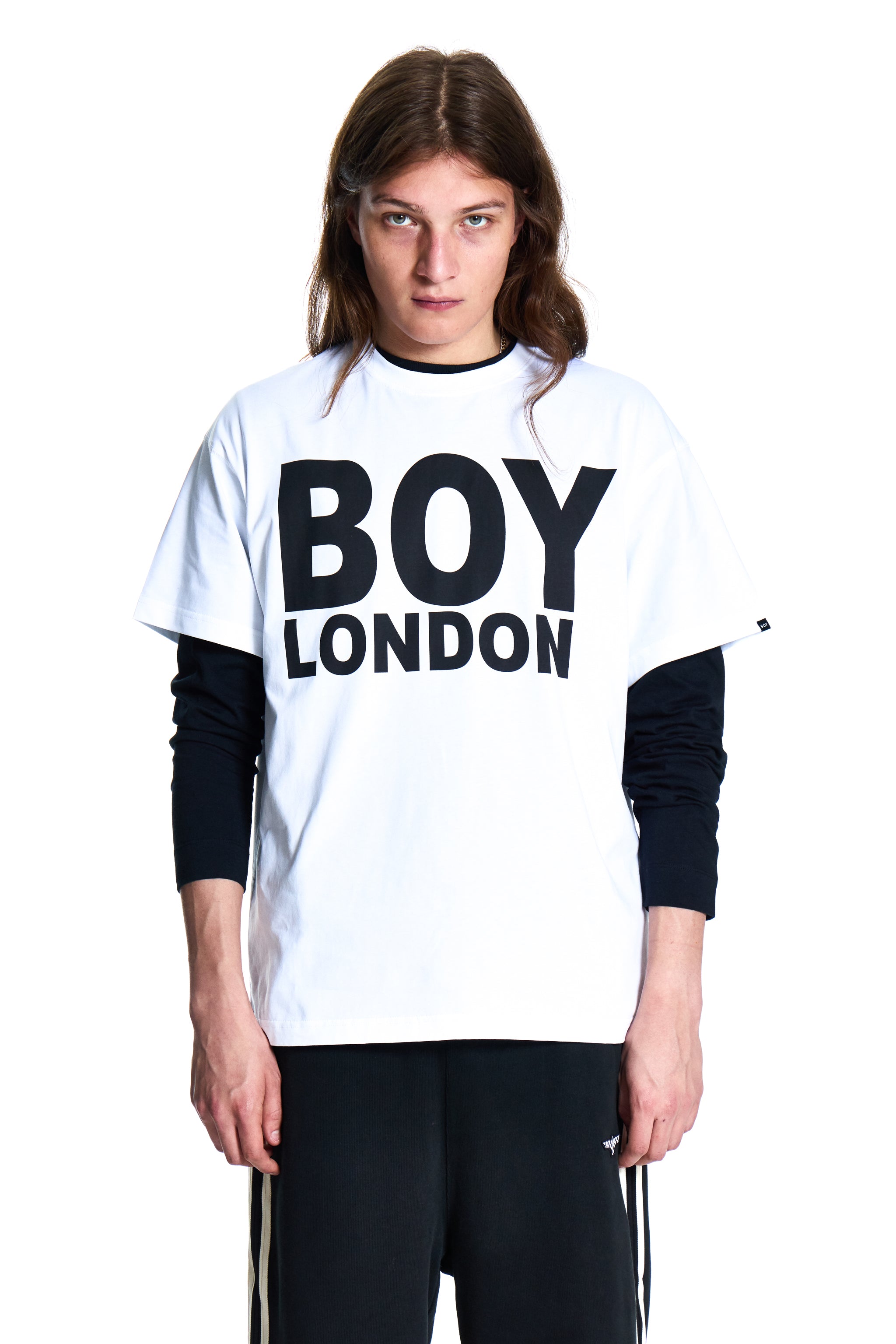 Person wearing a white 'BOY LONDON' shirt with black sleeves on a white background