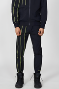 Person wearing a BOY London black tracksuit with yellow stripes on a white background