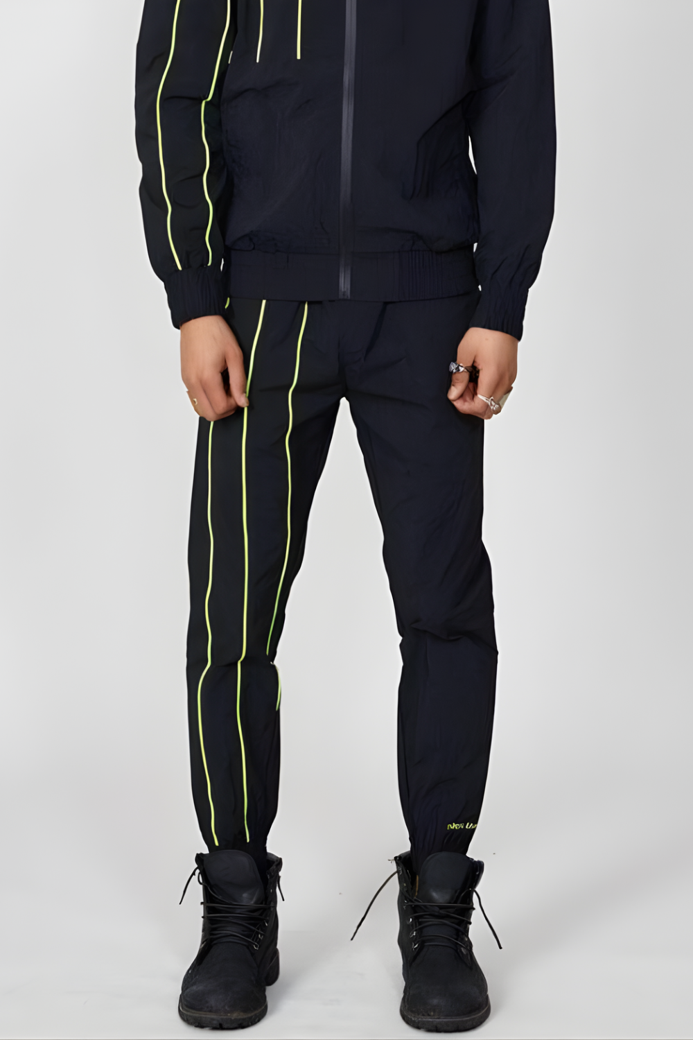 Person wearing a BOY London black tracksuit with yellow stripes on a white background