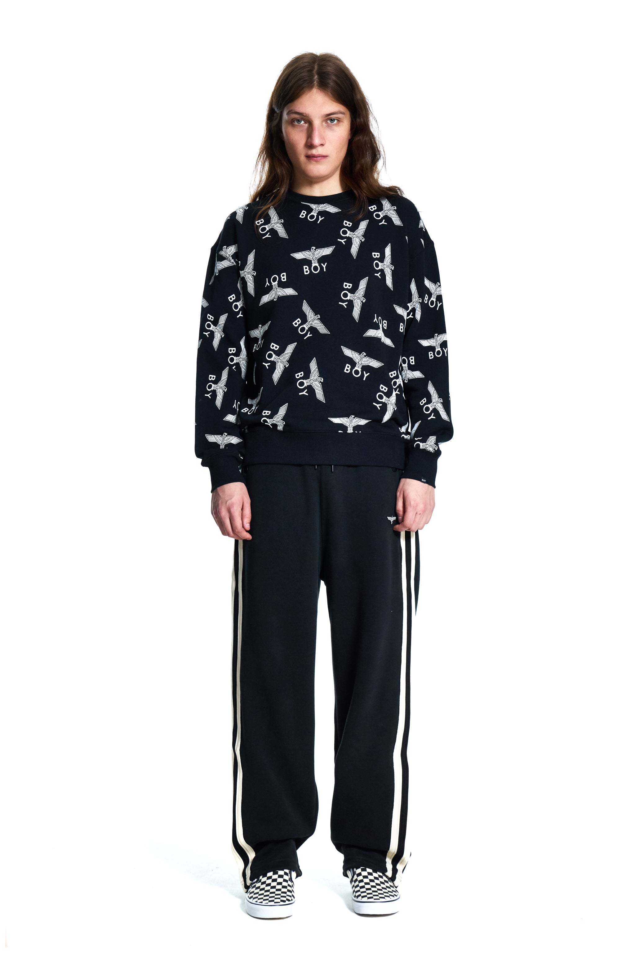 Person wearing a black Boy London sweater with white patterns and black pants with white stripes on a white background