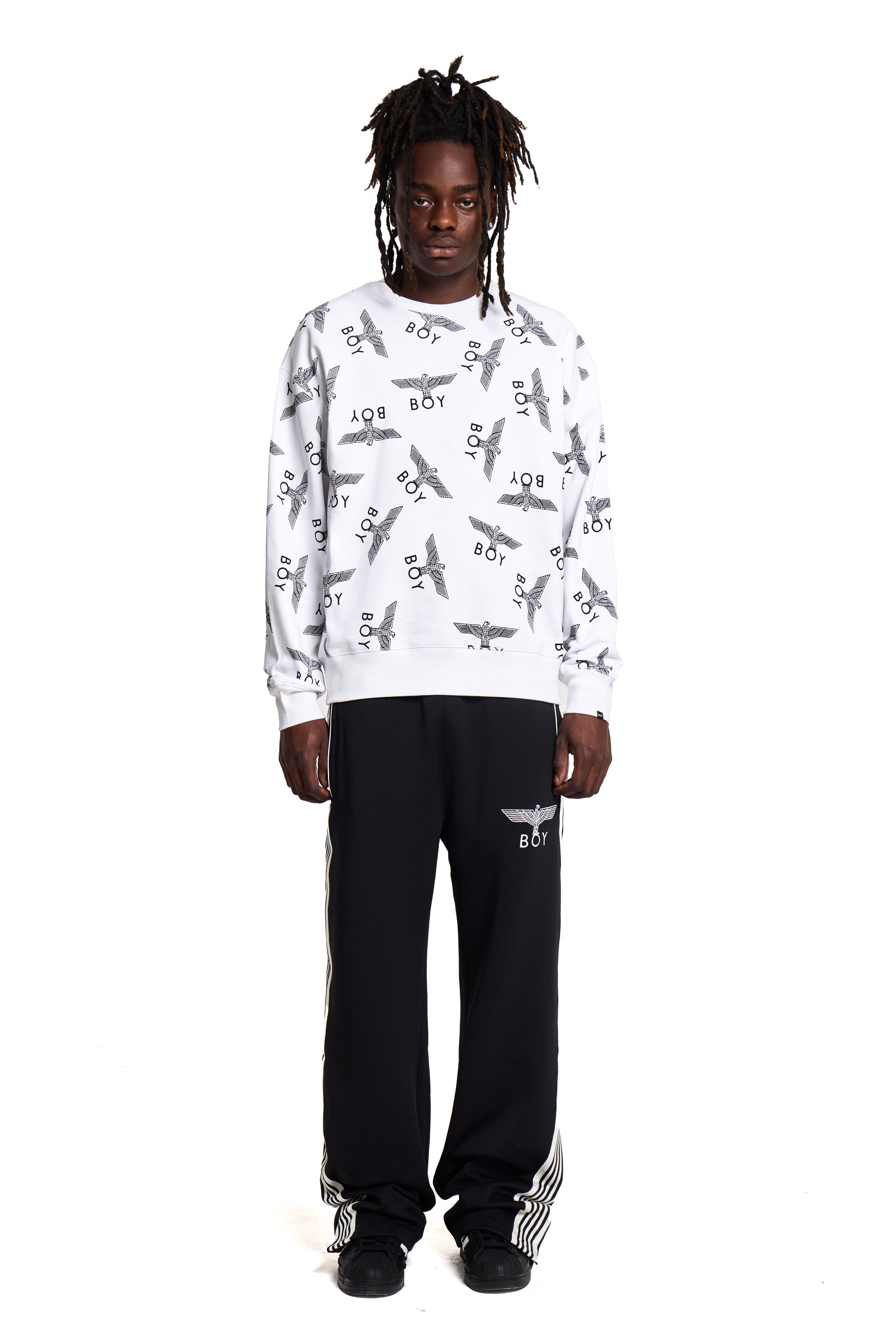 Person wearing a white Boy London sweatshirt with airplane pattern and black pants on a white background