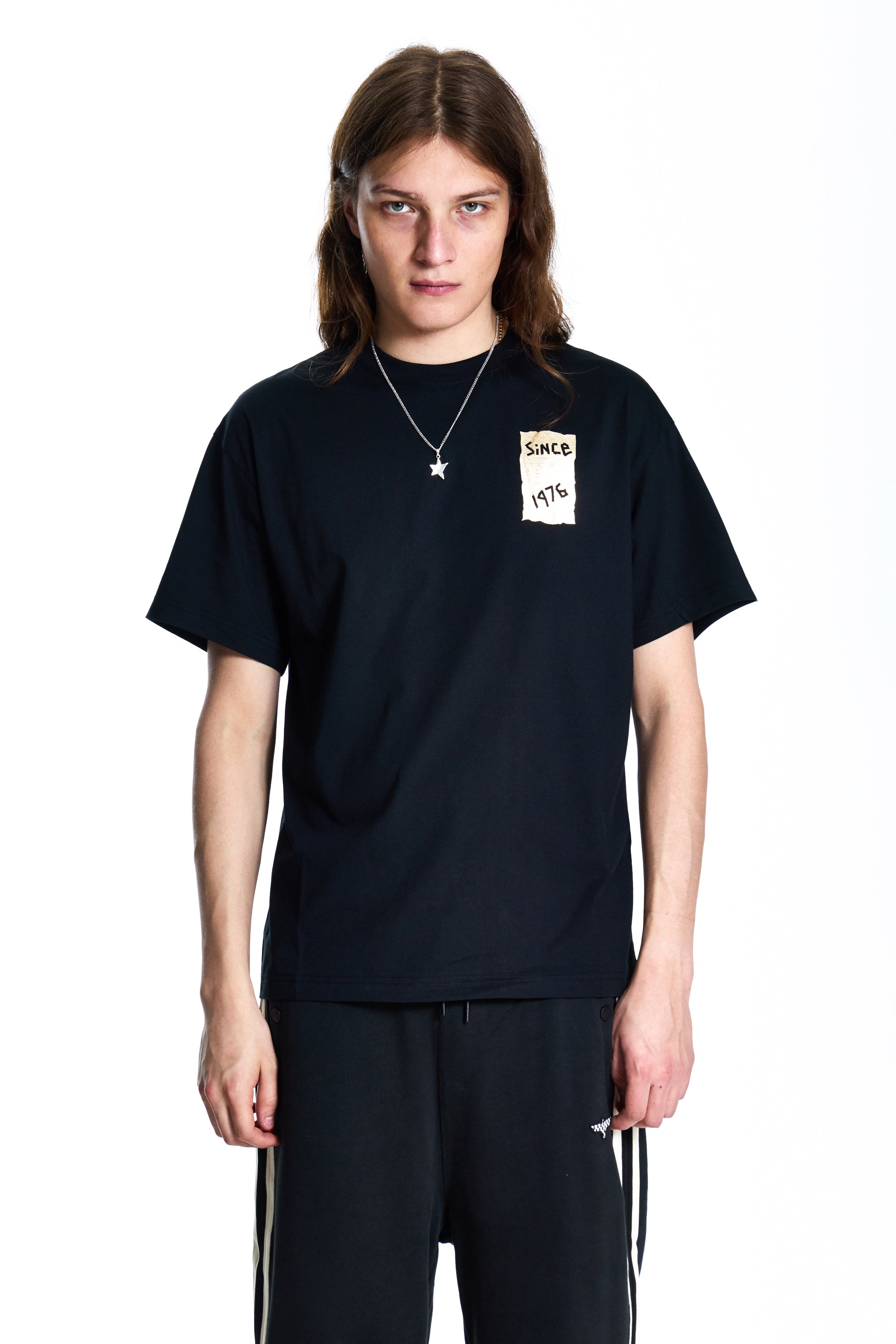 Person wearing a black t-shirt with a small graphic on a white background