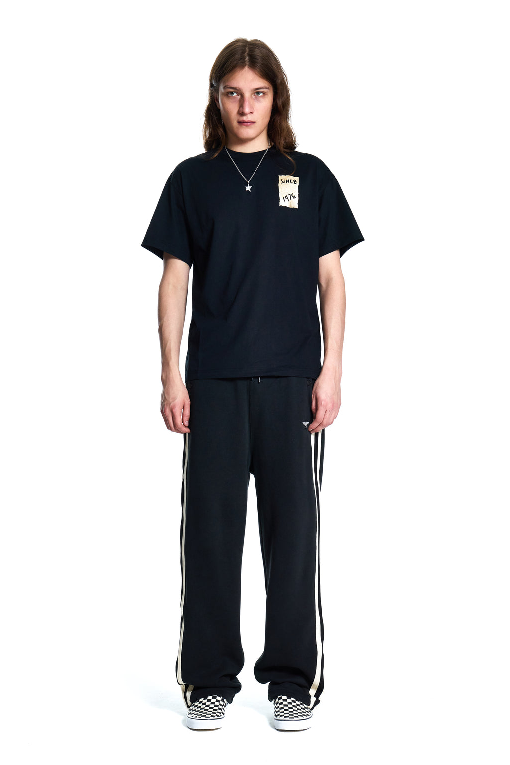 Person wearing a black t-shirt and black pants with white stripes on a white background