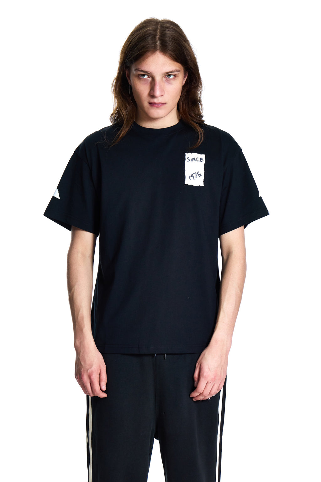 Person wearing a black t-shirt with a small white graphic on a white background
